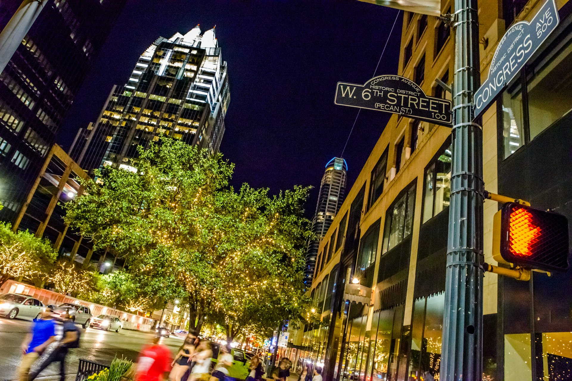 A street scene at night with people milling around in a blur