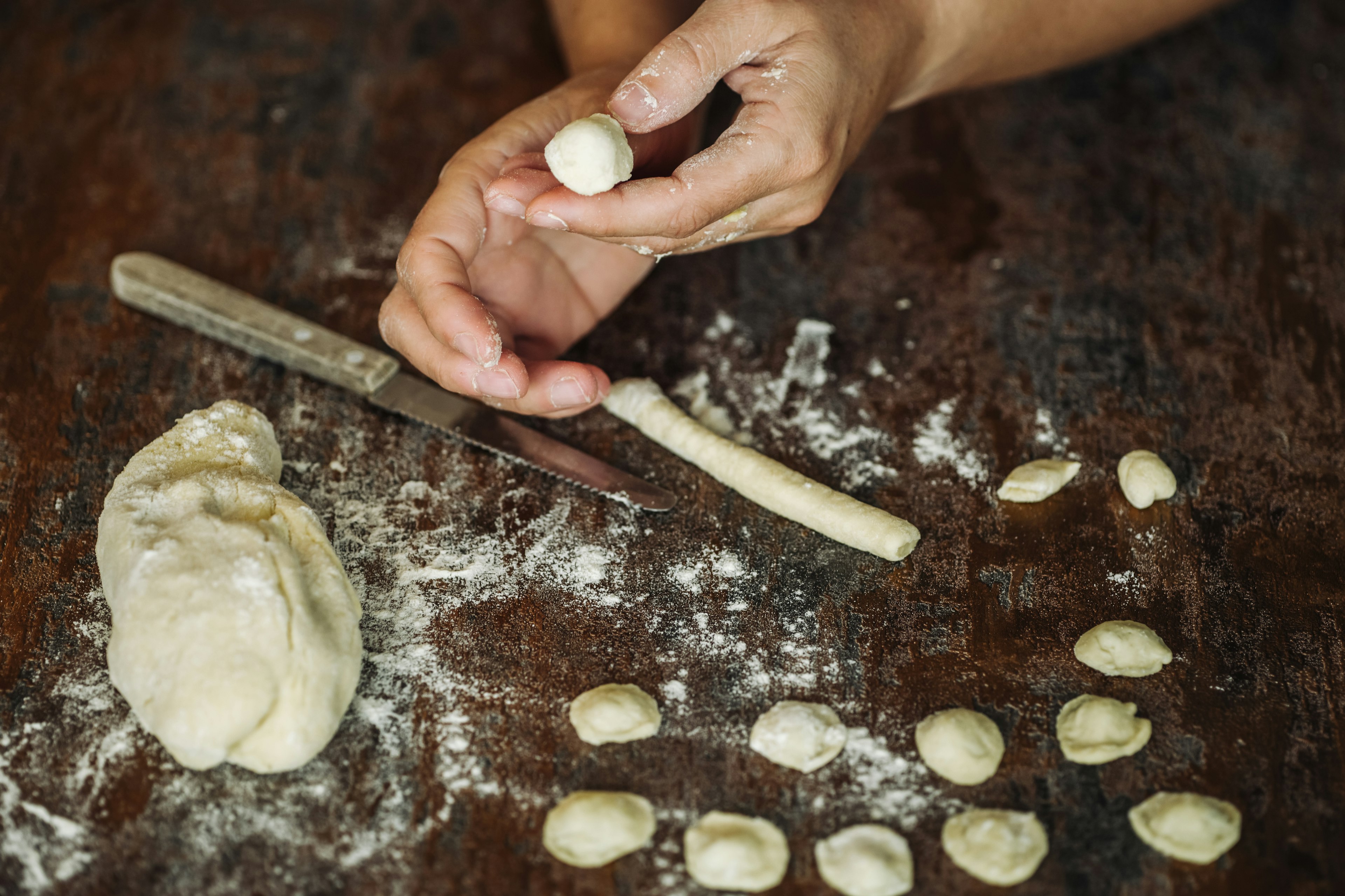 Hands mould a small piece of pasta into a cup shape, using their thumb