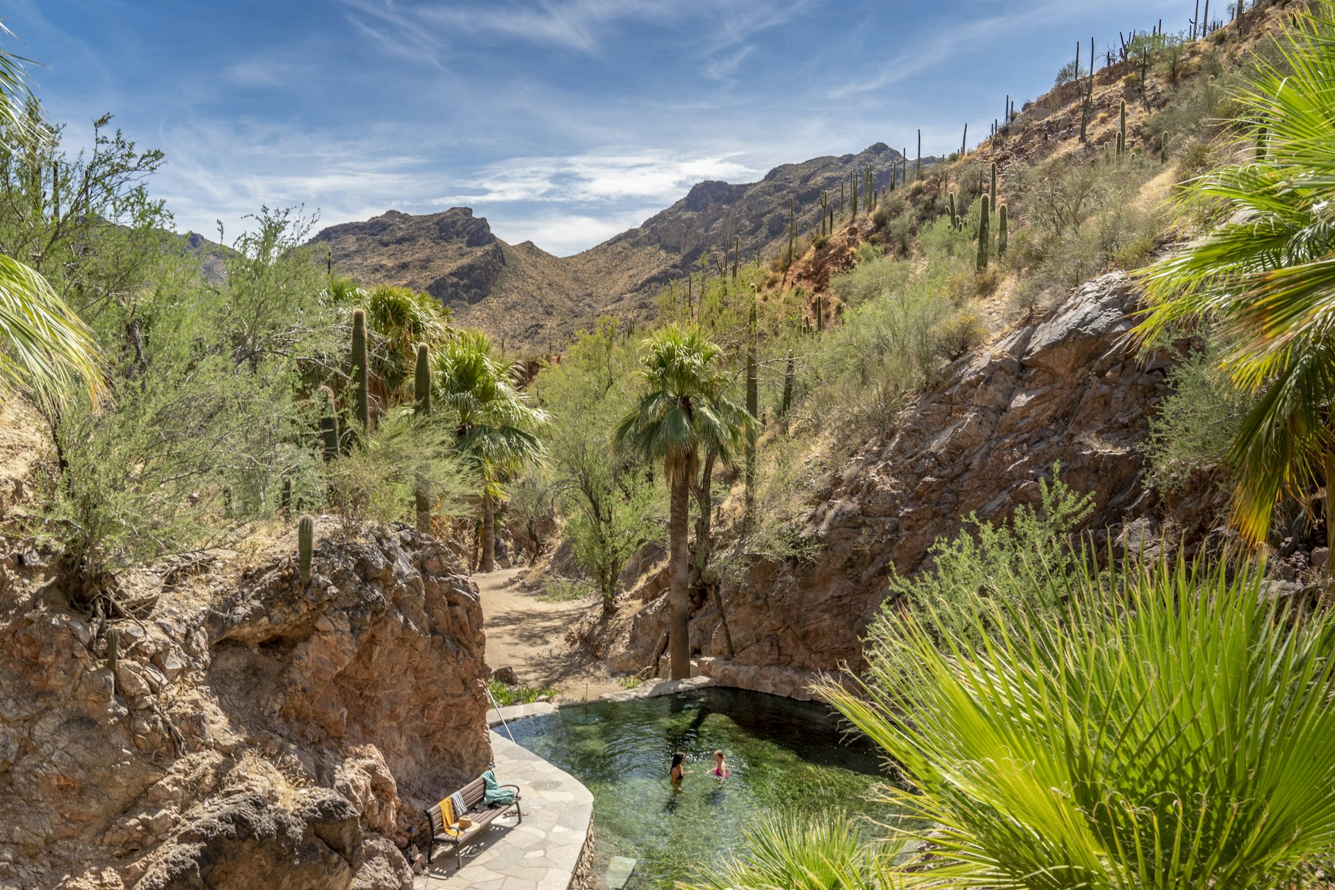 Two people in a hot spring set in a desert canyon landscape in Castle Hot Springs, Arizona, USA