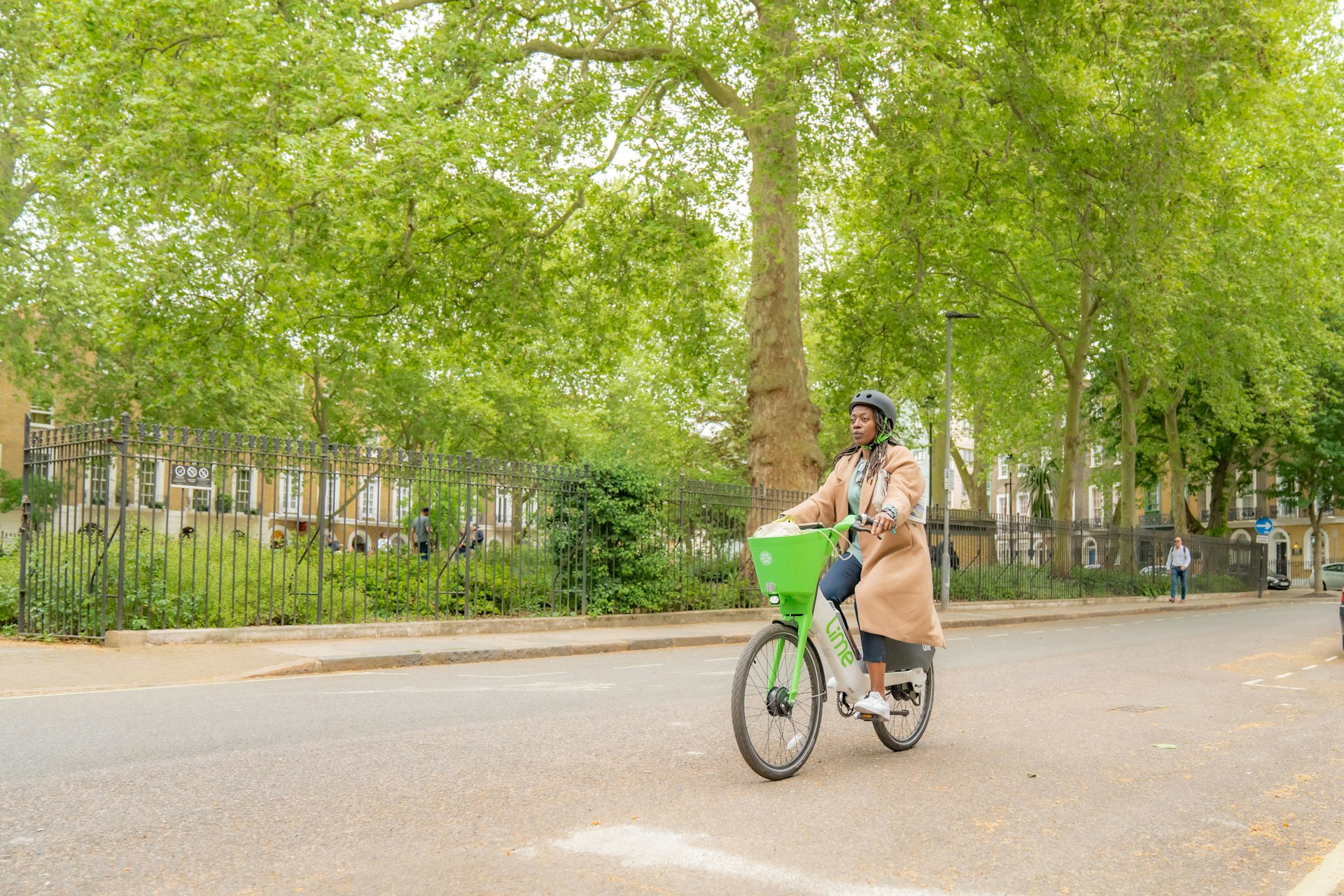 A woman on a Lime e-bike on a leafy street in London, England, United Kingdom
