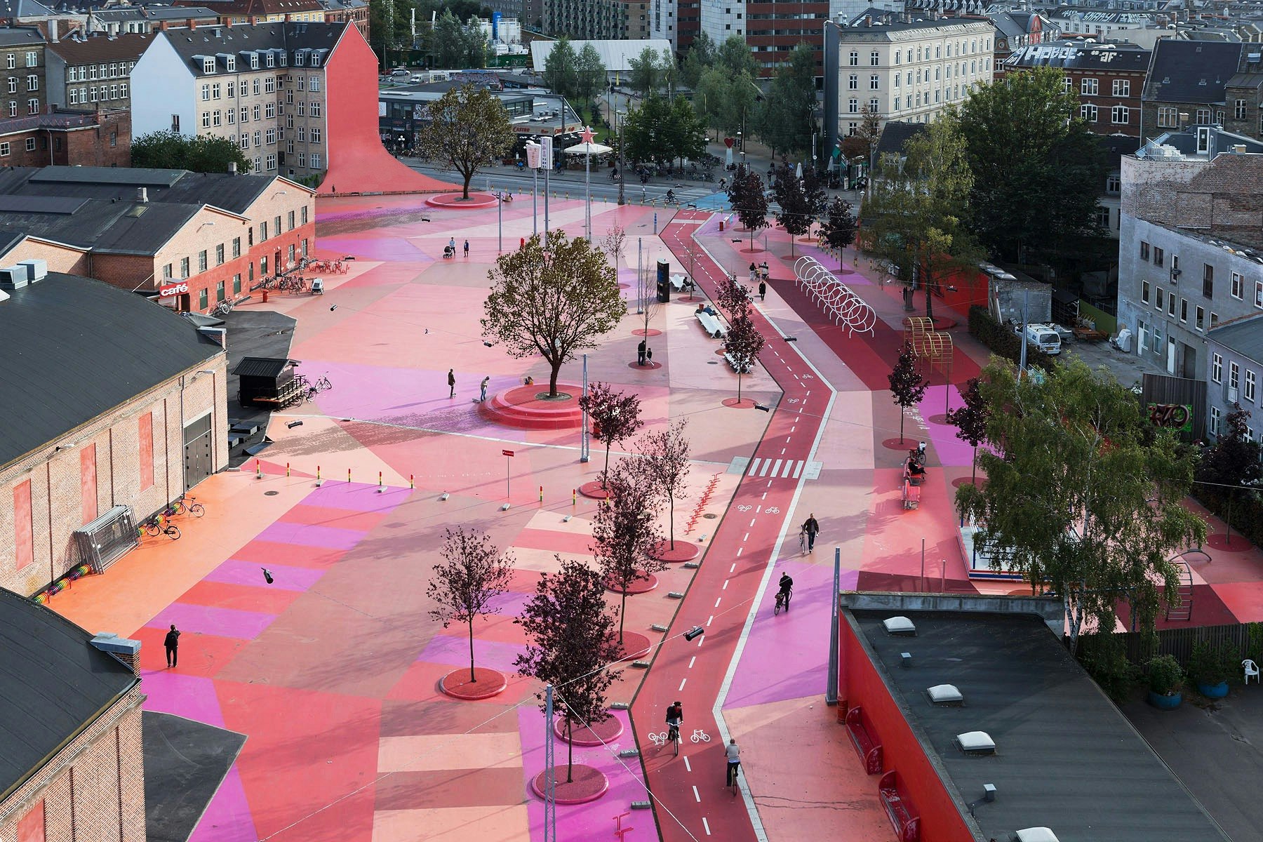 The ground is painted pink in an outdoor park, as seen from an aerial image. 