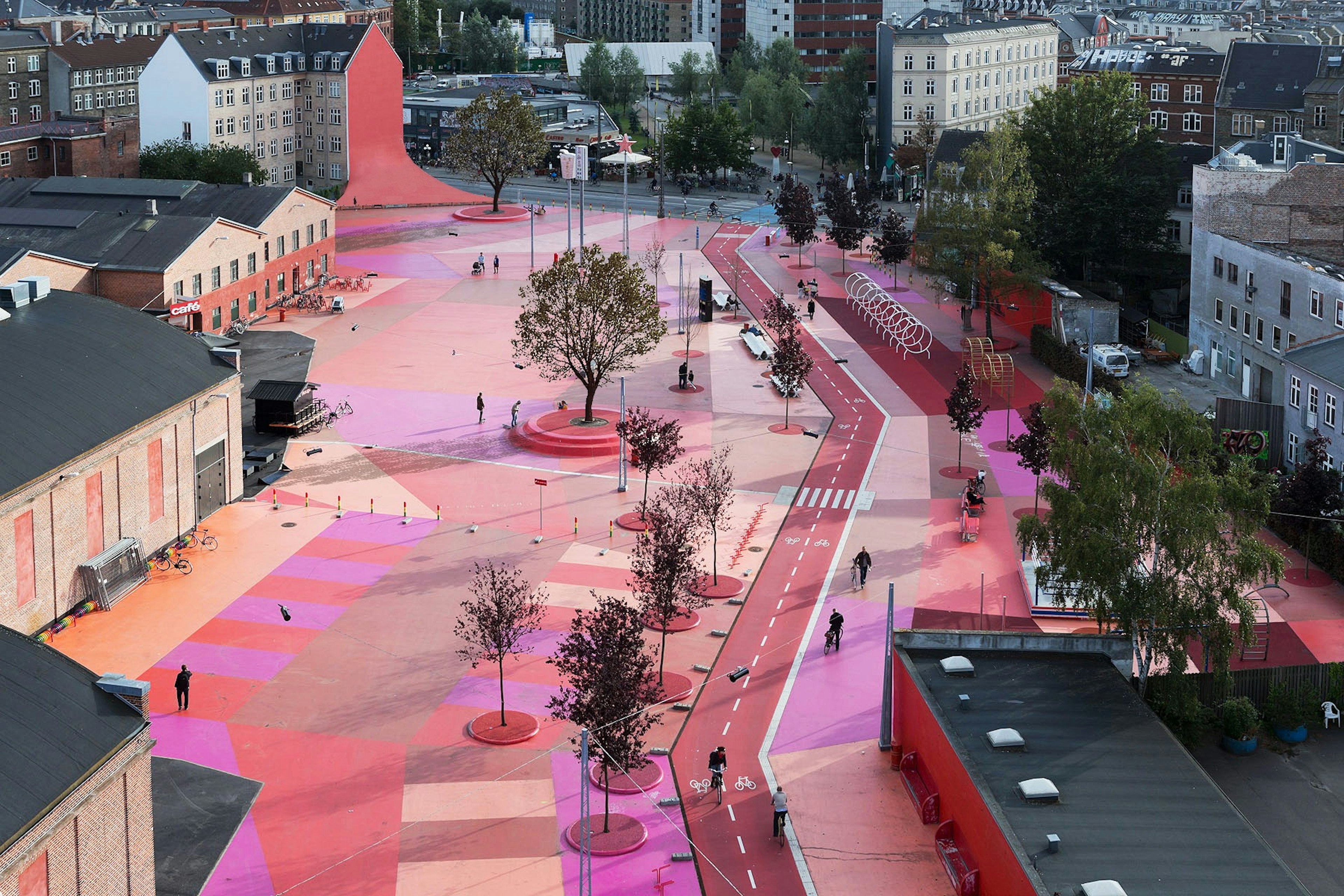 The ground is painted pink in an outdoor park, as seen from an aerial image.