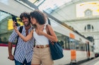 Man and woman, heterosexual couple going traveling with train together, standing on train station, using smart phone.
1170669413
Train station couple