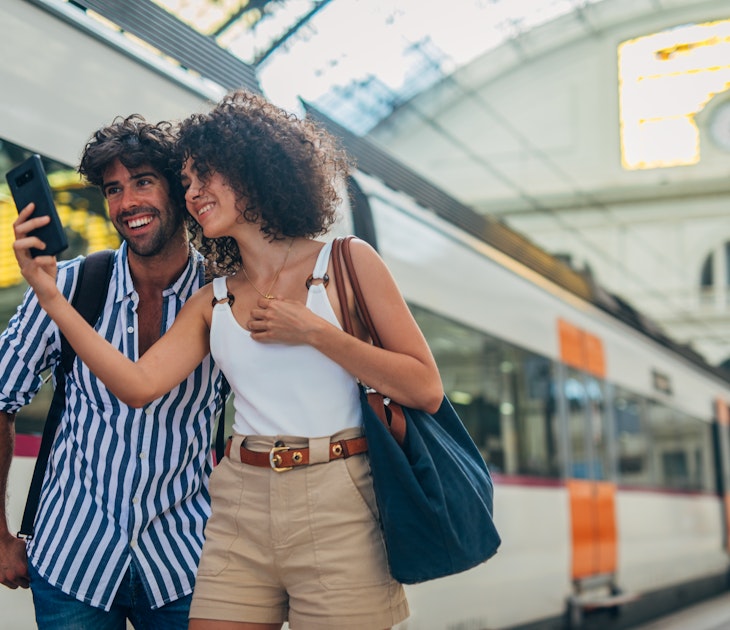 Man and woman, heterosexual couple going traveling with train together, standing on train station, using smart phone.
1170669413
Train station couple