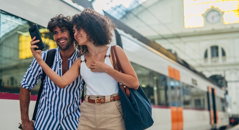 Man and woman, heterosexual couple going traveling with train together, standing on train station, using smart phone.
1170669413
Train station couple