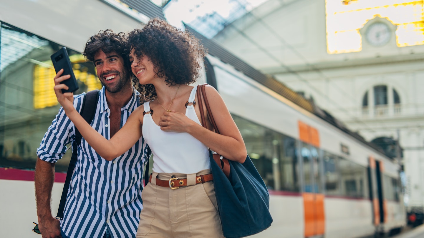 Man and woman, heterosexual couple going traveling with train together, standing on train station, using smart phone.
1170669413
Train station couple