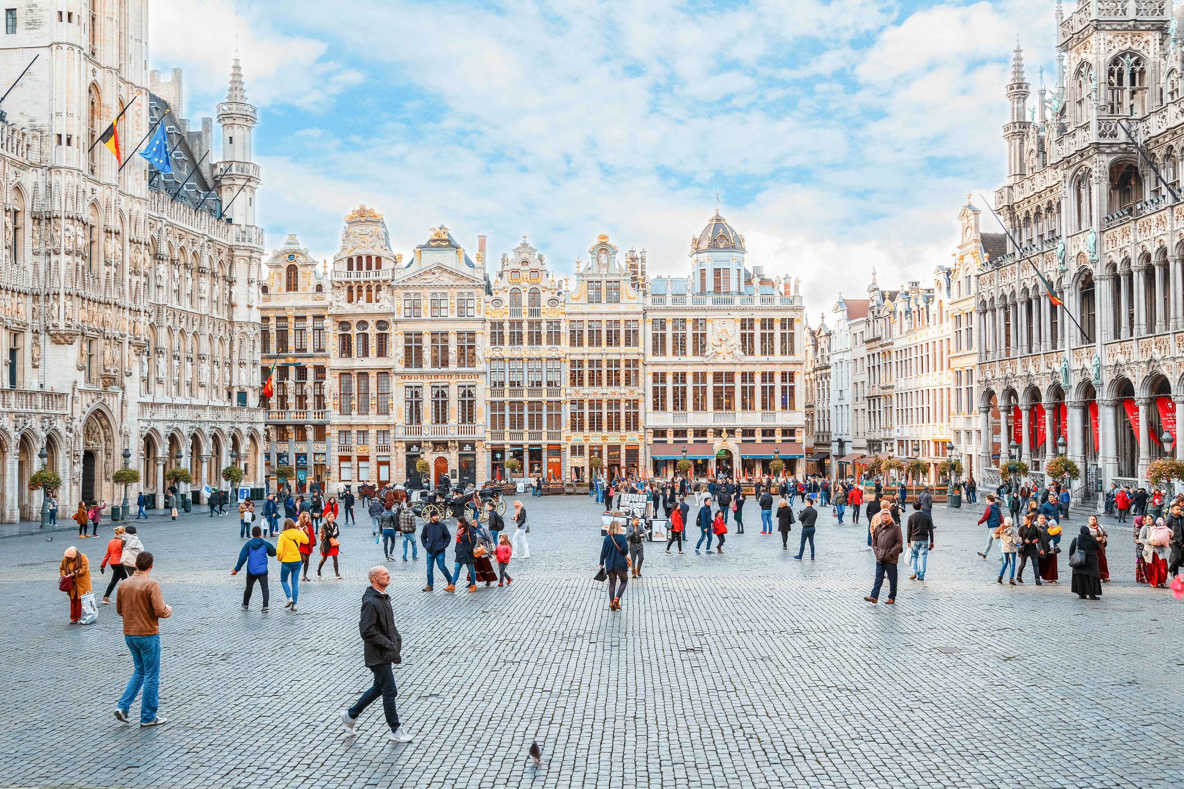 Pedestrians in a large city square with cobbled streets