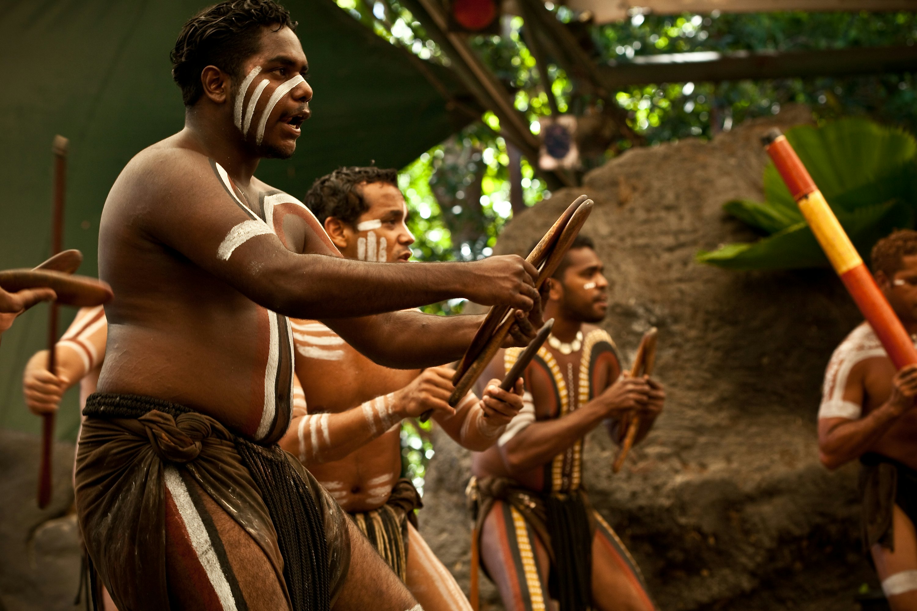 Performers sing and dance on stage in a demonstration of Aboriginal culture