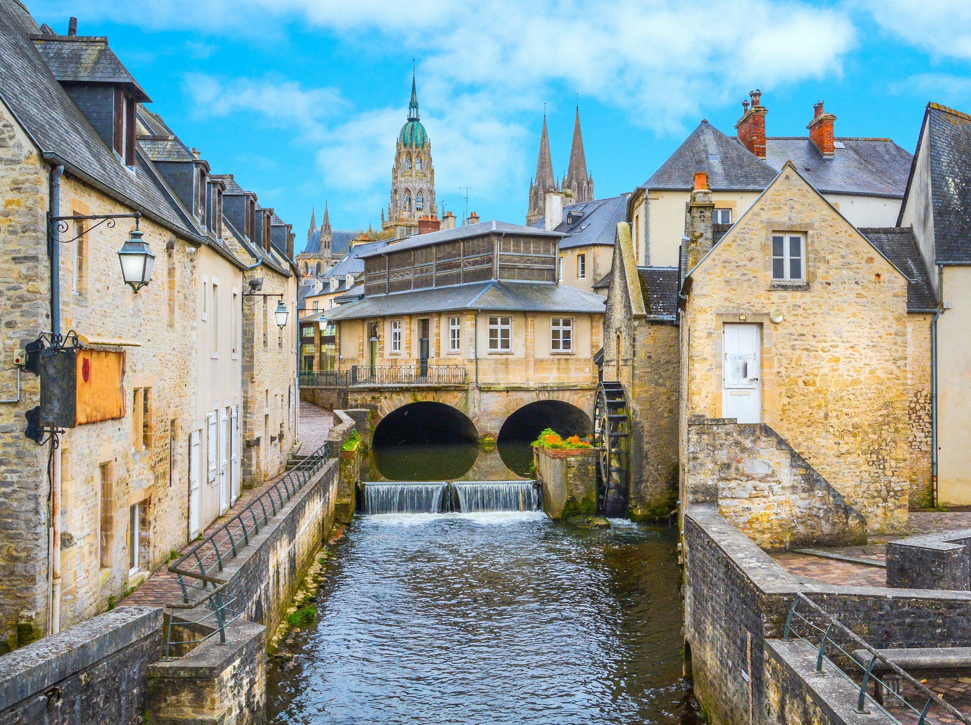 A small river runs between buildings in a town with Gothic architecture
