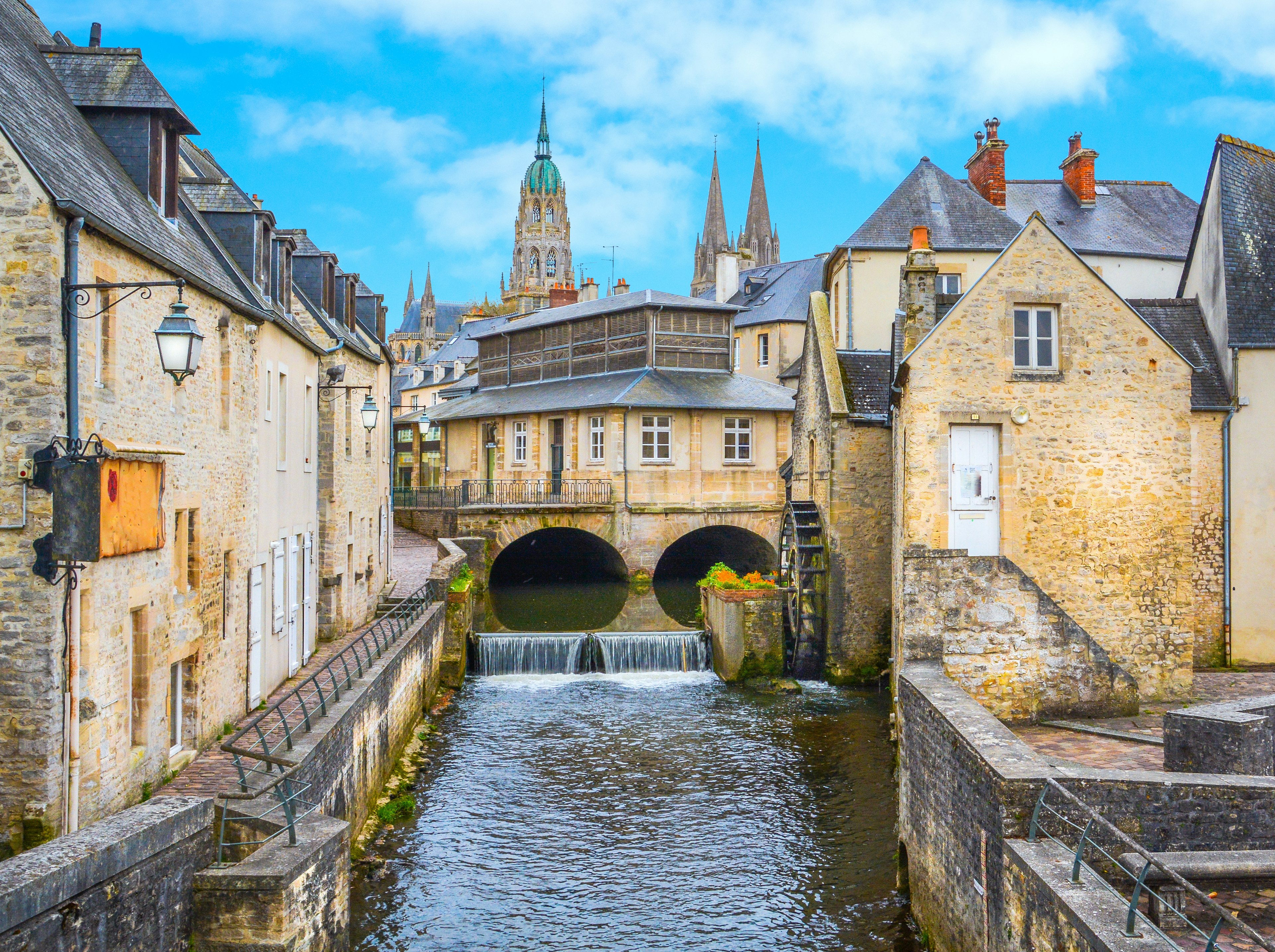 A small river runs between buildings in a town with Gothic architecture