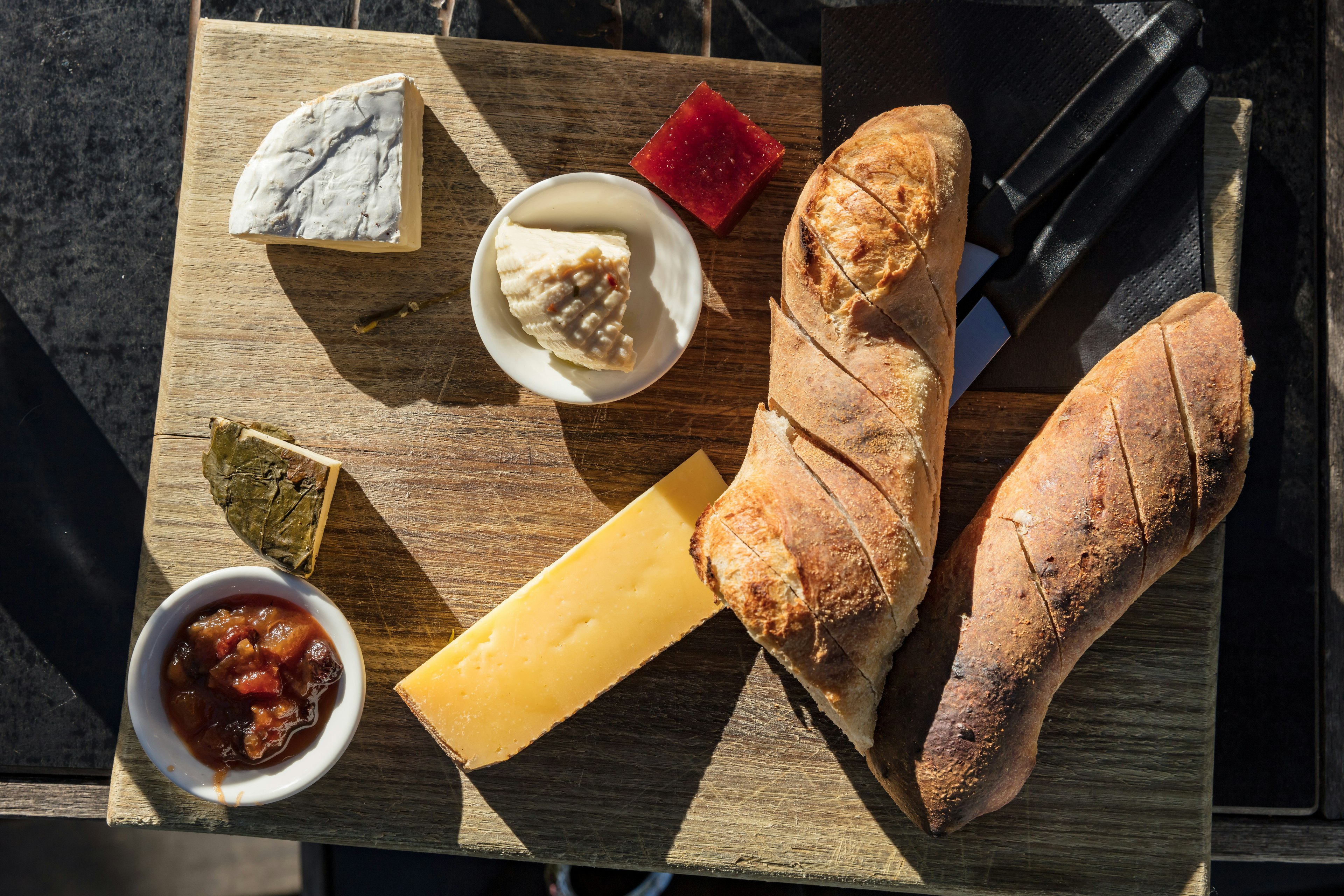 Cheese and bread platter enjoyed outdoors on a sunny day on Bruny island, Tasmania.