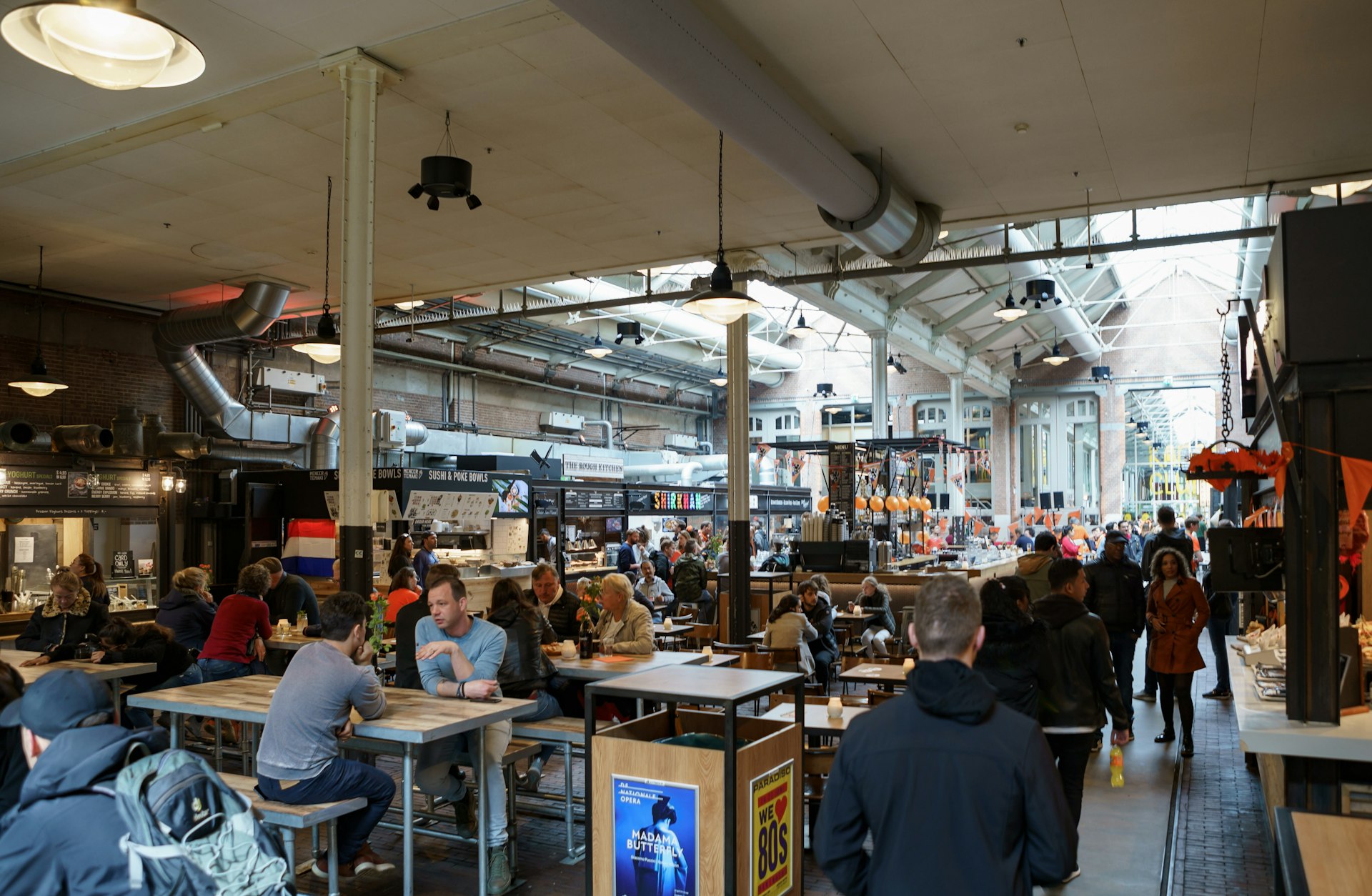 The interior of Foodhallen in Amsterdam with people eating at shared tables
