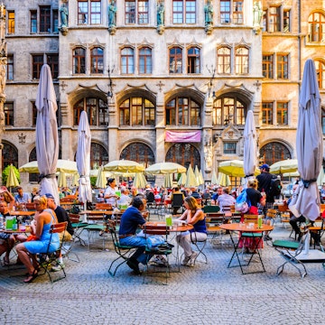 People seated on outdoor tables at Marienplatz in Munich.

