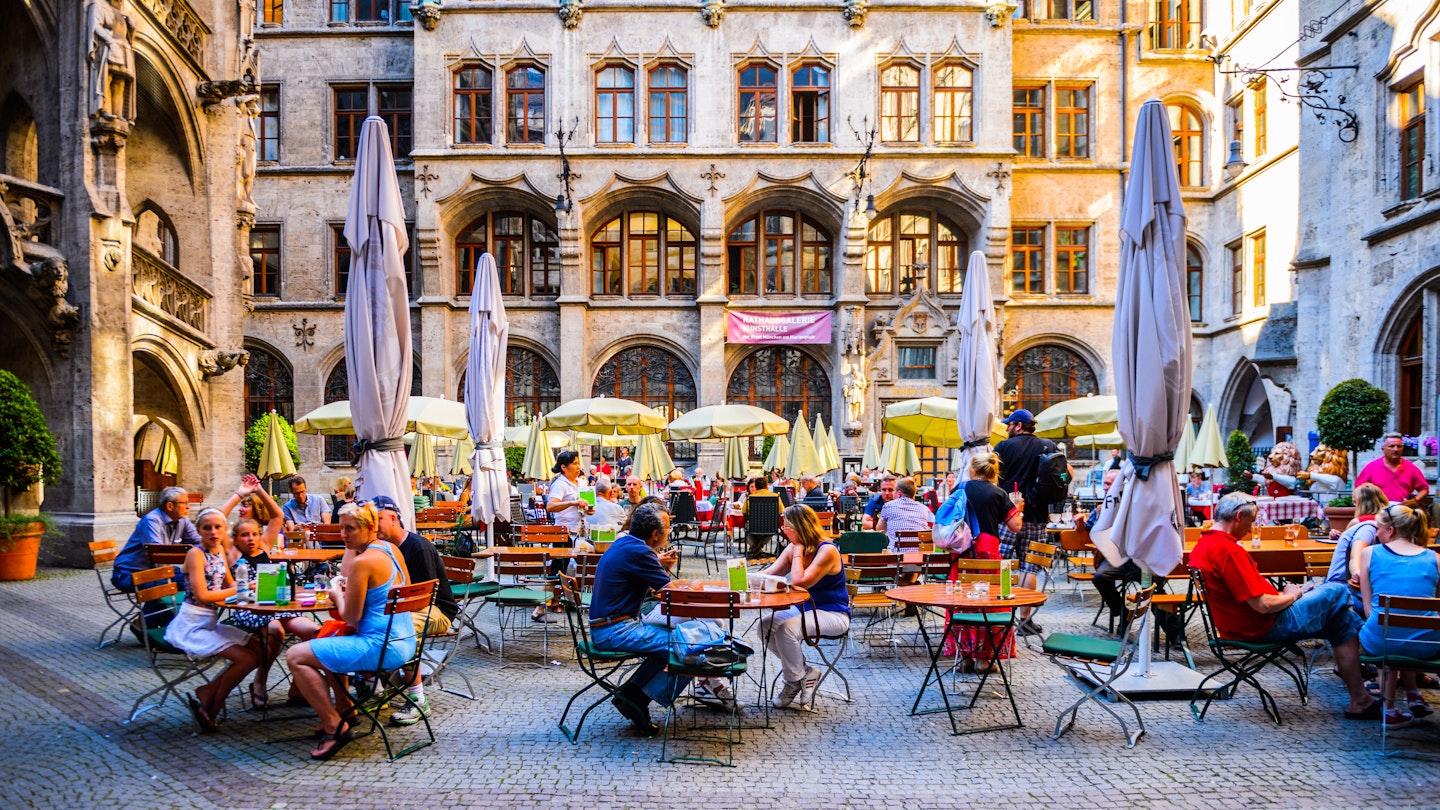 People seated on outdoor tables at Marienplatz in Munich.
