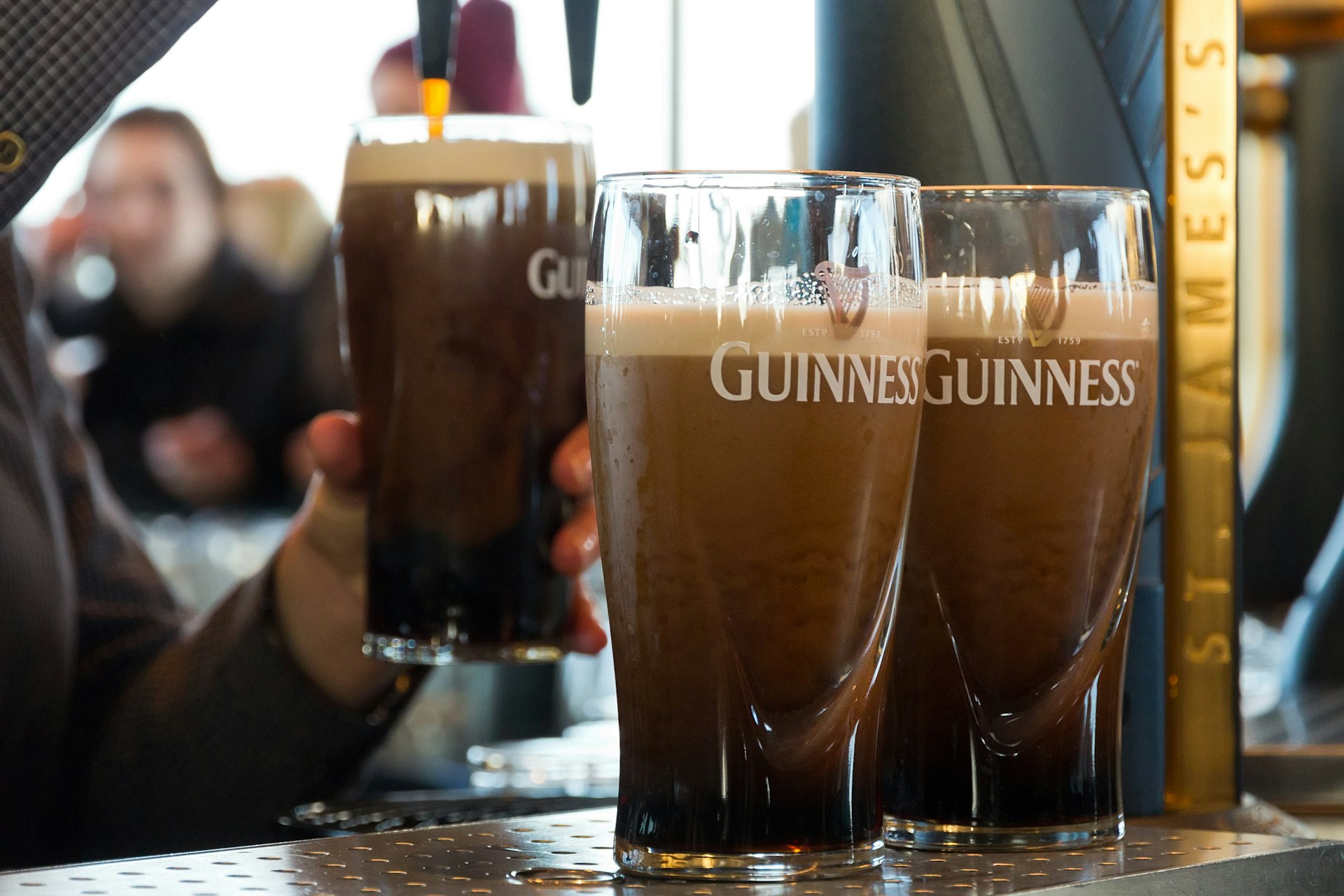 Три пинты Гиннесса разливают в The Guinness Storehouse в Дублине, Ирландия.