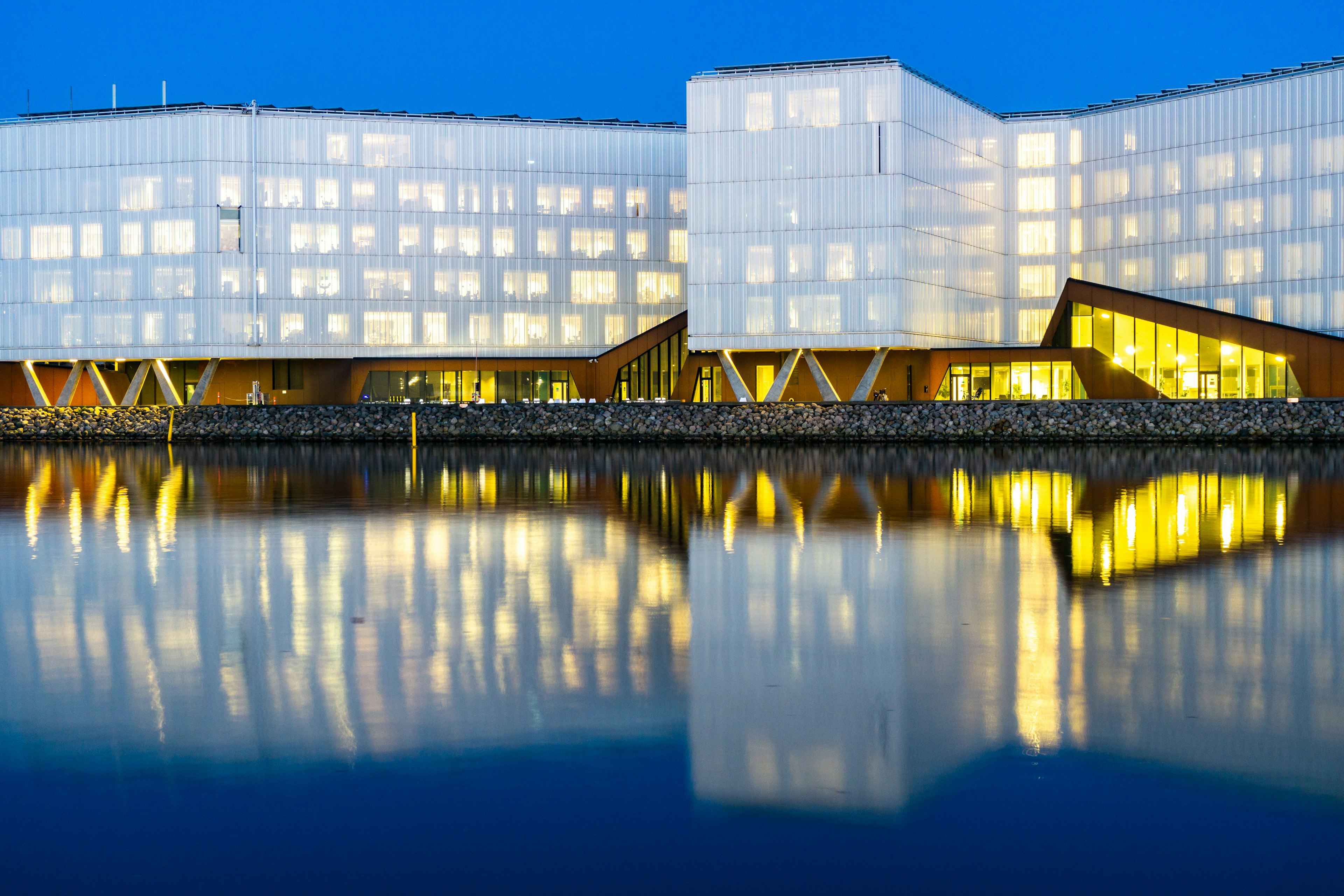 The UN City building reflected in the water by night, Nordhavn, Copenhagen, Denmark