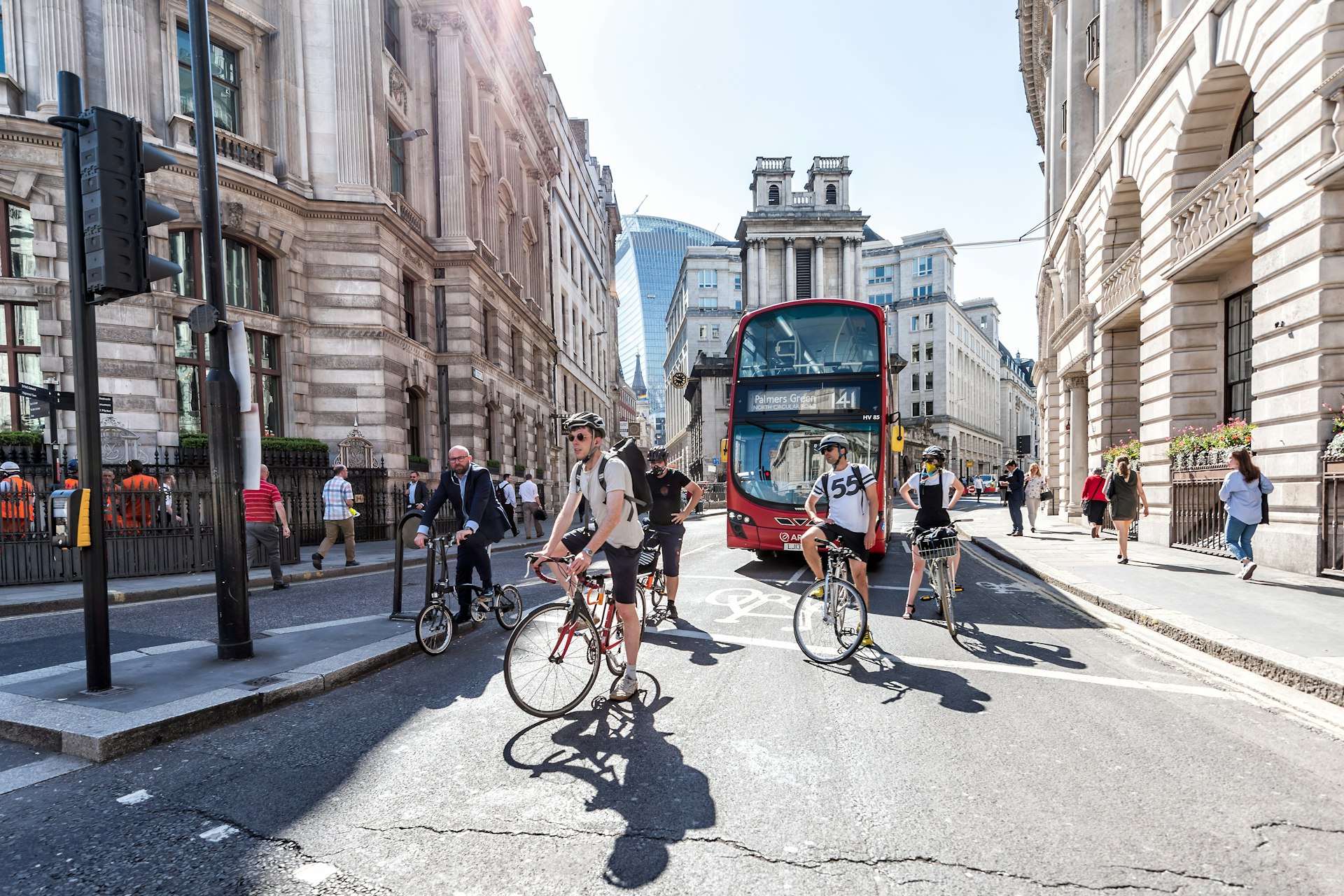 Several cyclists stop at a red light with a double-decker bus behind on a street in the City, London, England, United Kingdom