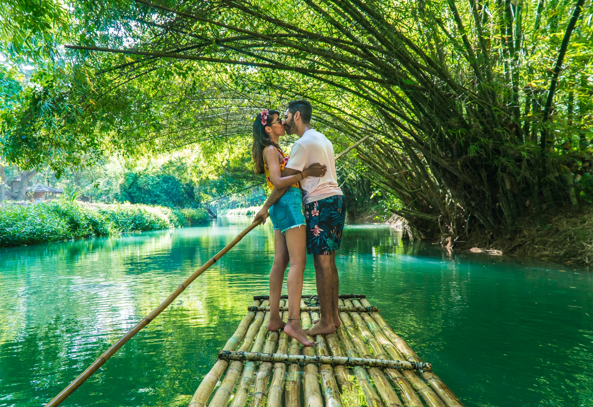 Happy couple kissing and taking a romantic rafting ride down the Martha Brae River, Jamaica