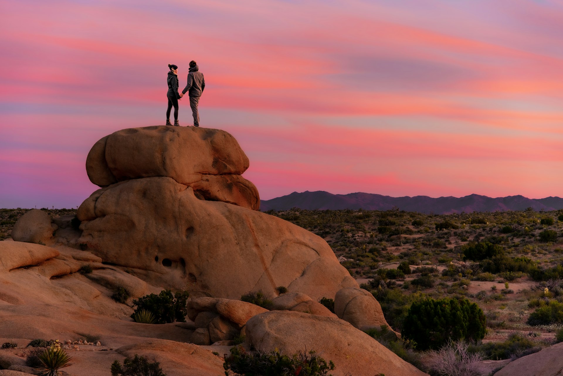 Couple standing on a rock at sunset in Joshua Tree National Park, California, USA