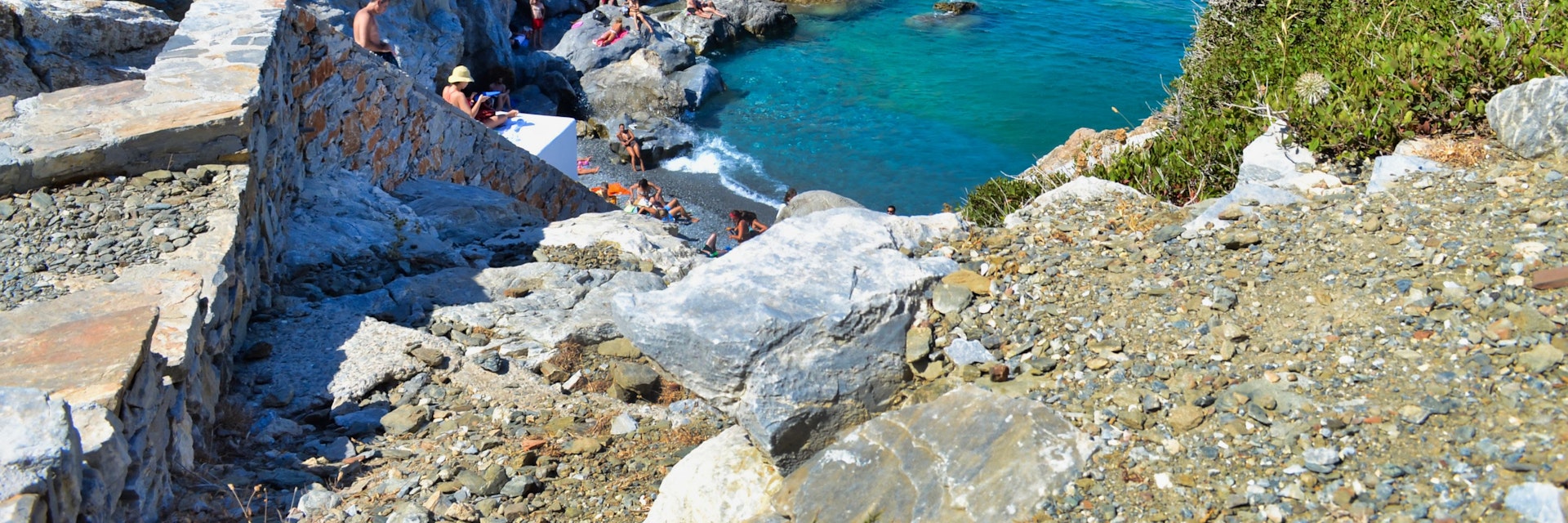 People sunbathing on the rocks in Agia Anna beach at Amorgos island of Greece.