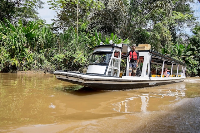 A traditional passenger boat navigating the muddy-looking Tortuguero canal in Costa Rica