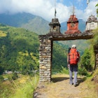 A man enters the gate to nepalese village at the valley on Annapurna Circuit Trek in Nepal.

