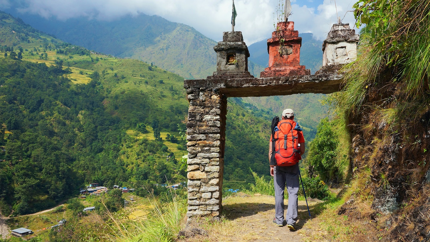 A man enters the gate to nepalese village at the valley on Annapurna Circuit Trek in Nepal.
