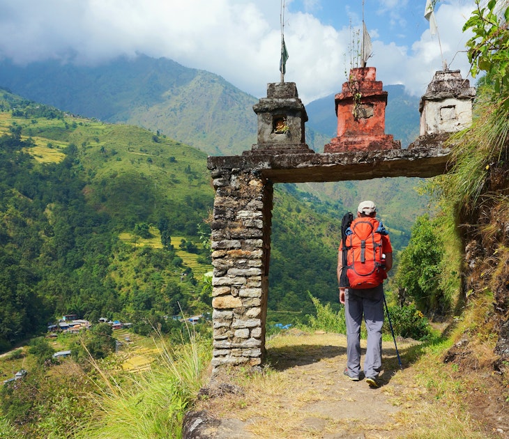 A man enters the gate to nepalese village at the valley on Annapurna Circuit Trek in Nepal.