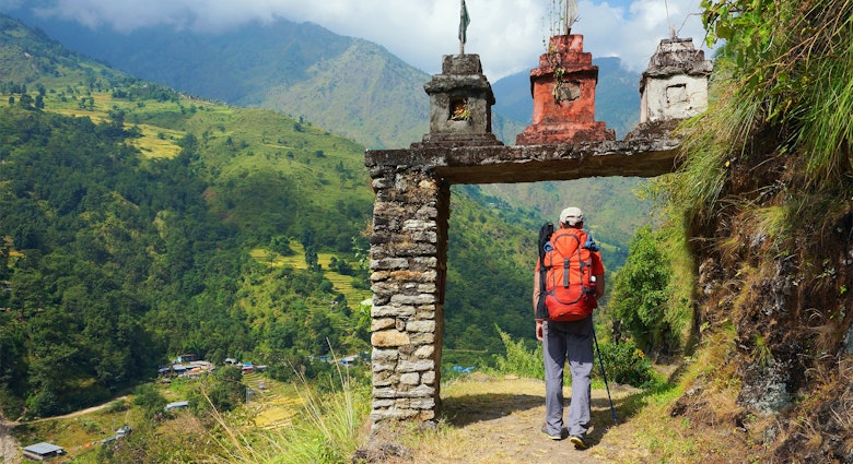 A man enters the gate to nepalese village at the valley on Annapurna Circuit Trek in Nepal.
