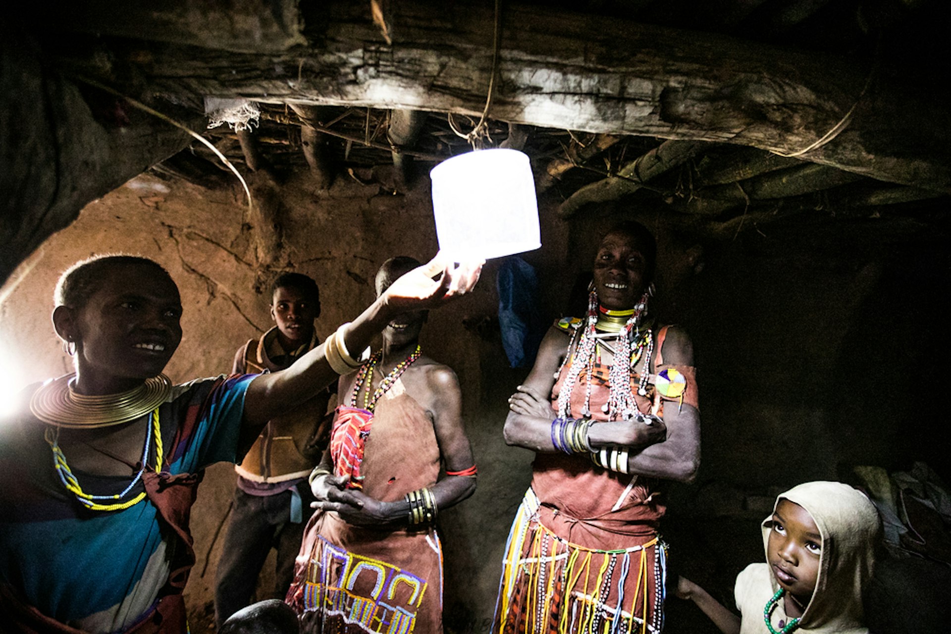 People in a dark space smile as someone holds up a small solar-powered light 