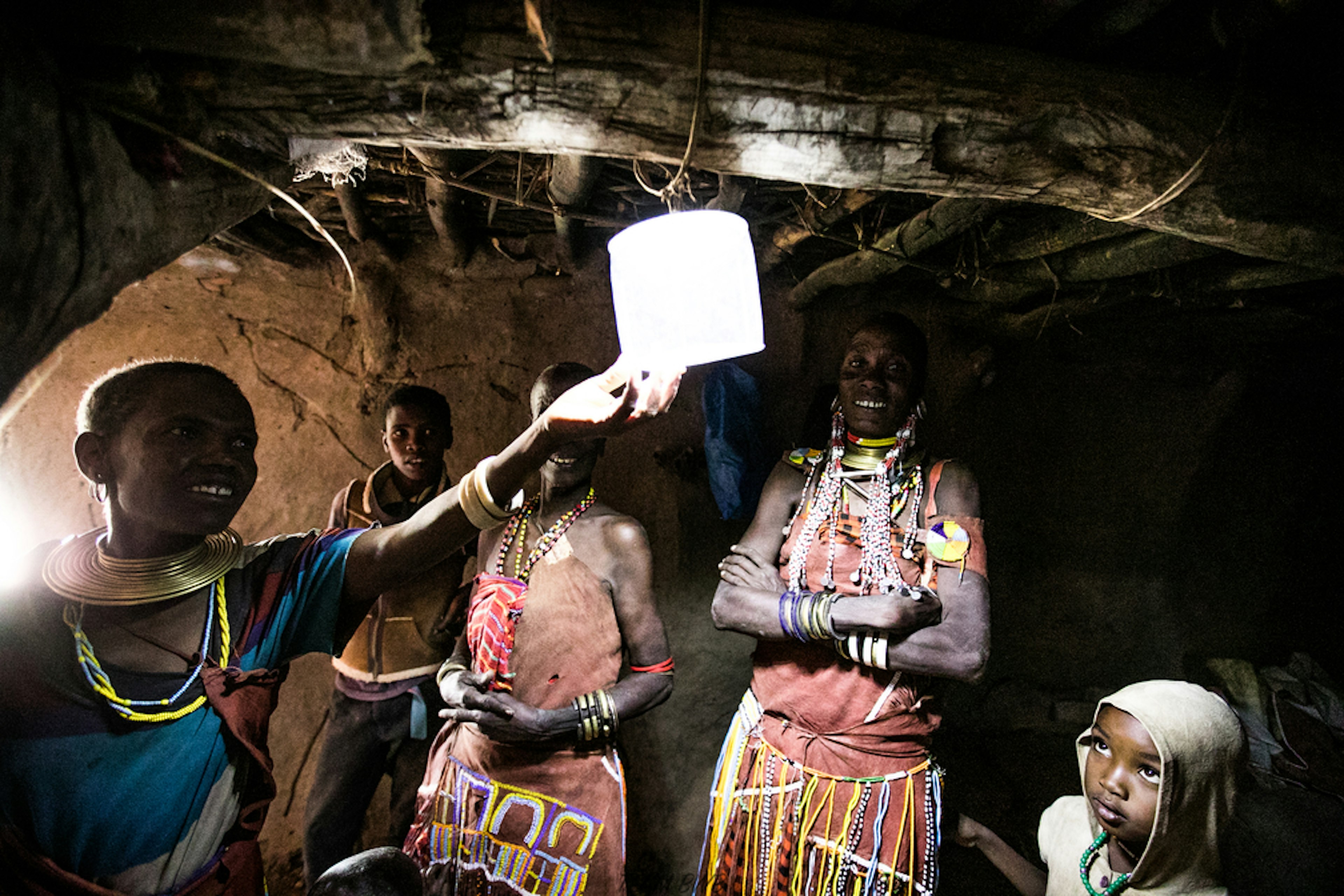 People in a dark space smile as someone holds up a small solar-powered light