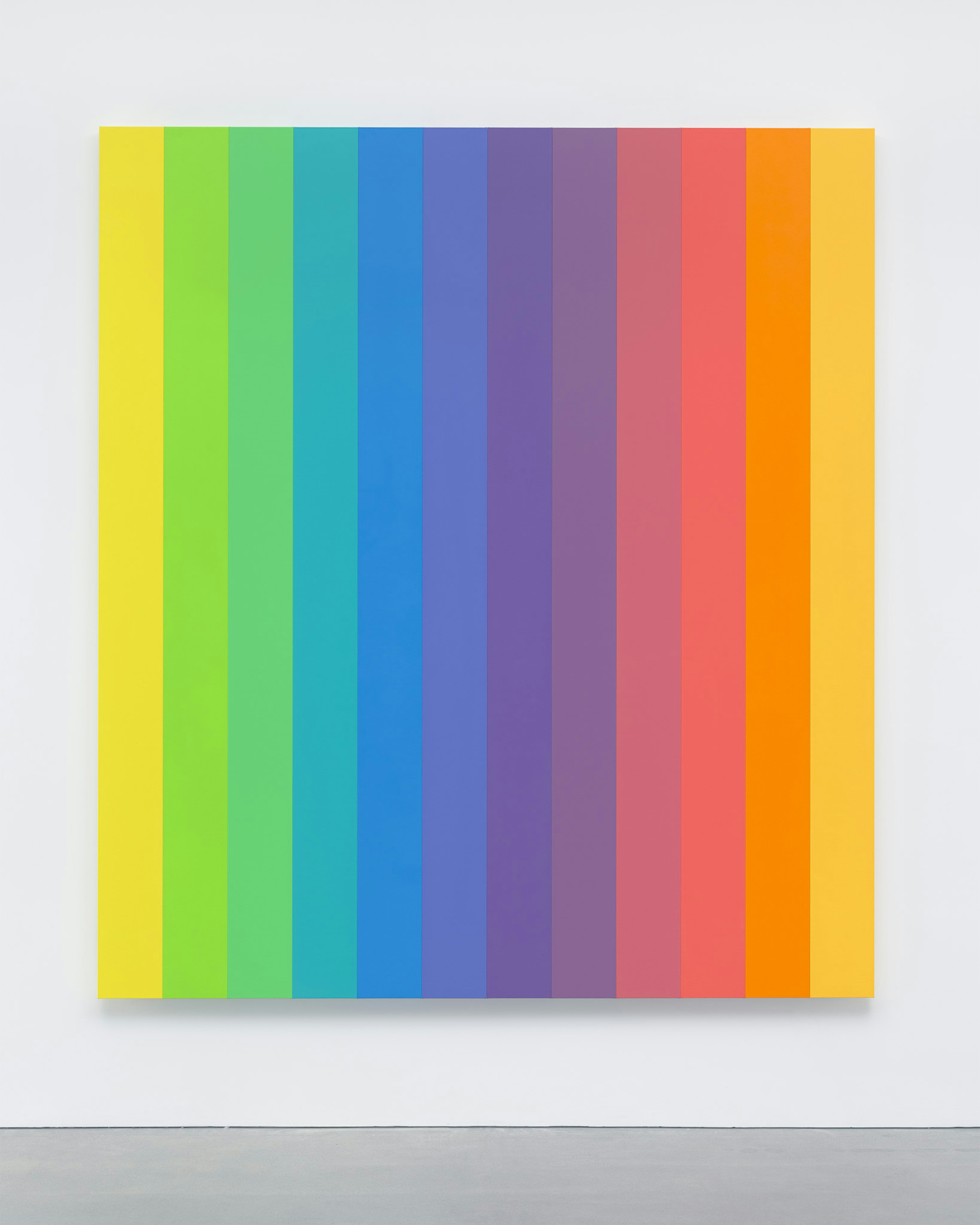 A rainbow-stripe piece of art hangs on a gallery wall.