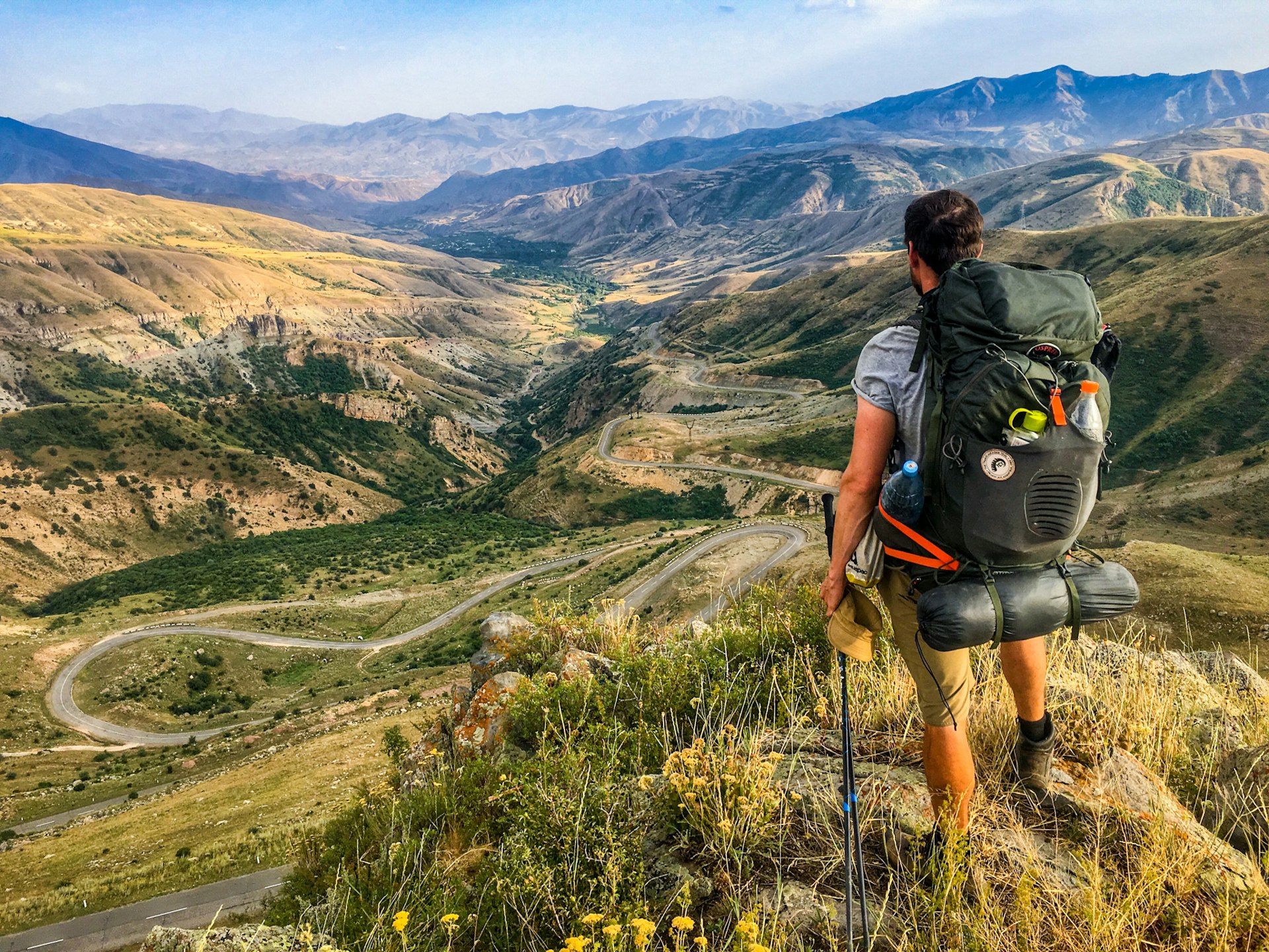 A hiker with a backpack looks out at a valley view in the mountains, Transcaucasian Trail, Armenia