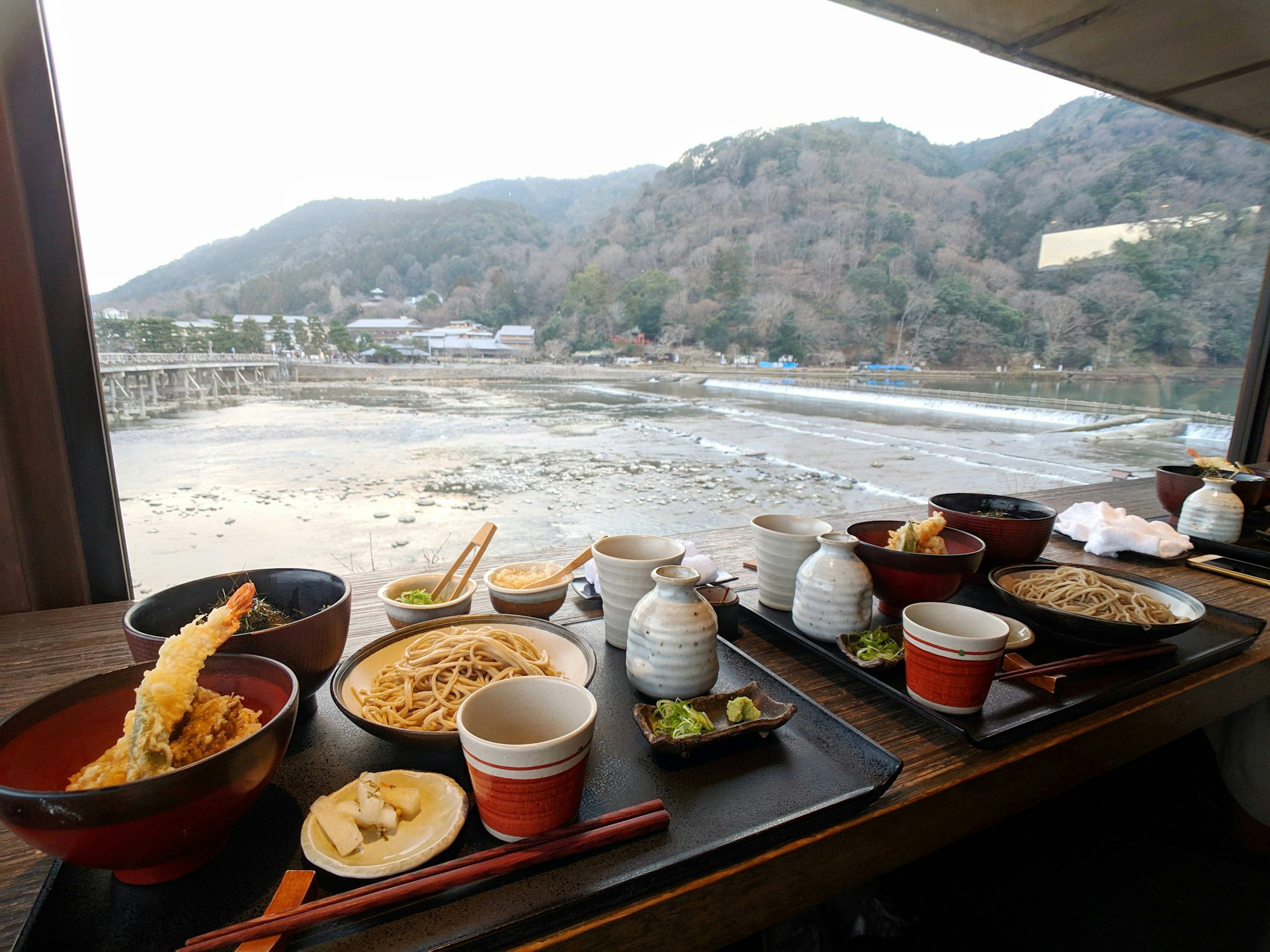 Two trays of food placed at a window seat in a restaurant with a river view