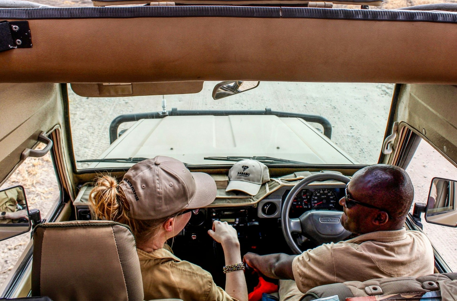 Two people sat in the front seats of a 4WD on a game drive