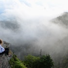 A teenage girl sits and watches drifting clouds at the summit of Mount LeConte in the Great Smoky Mountains National Park.