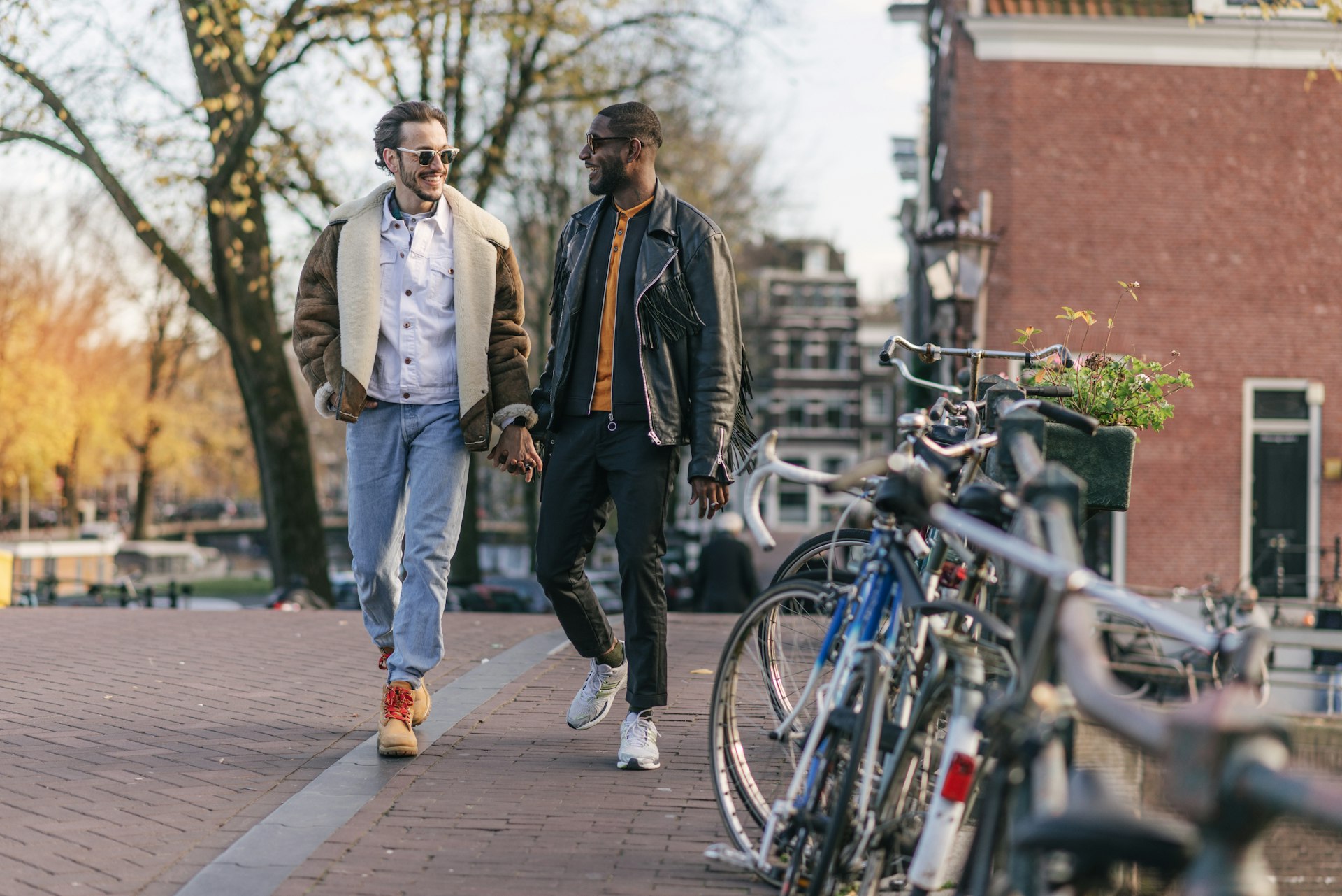 A male couple holds hands on a walk around the canals of Amsterdam, Netherlands