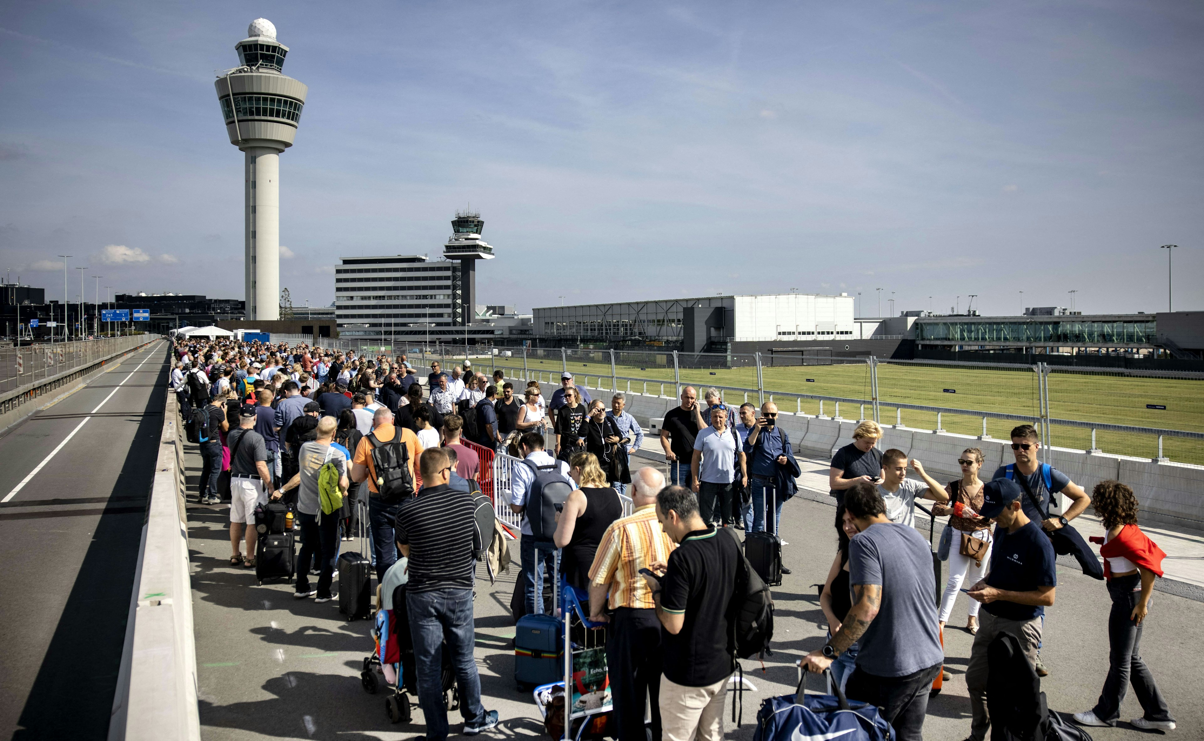 Travelers queue at Schiphol Airport