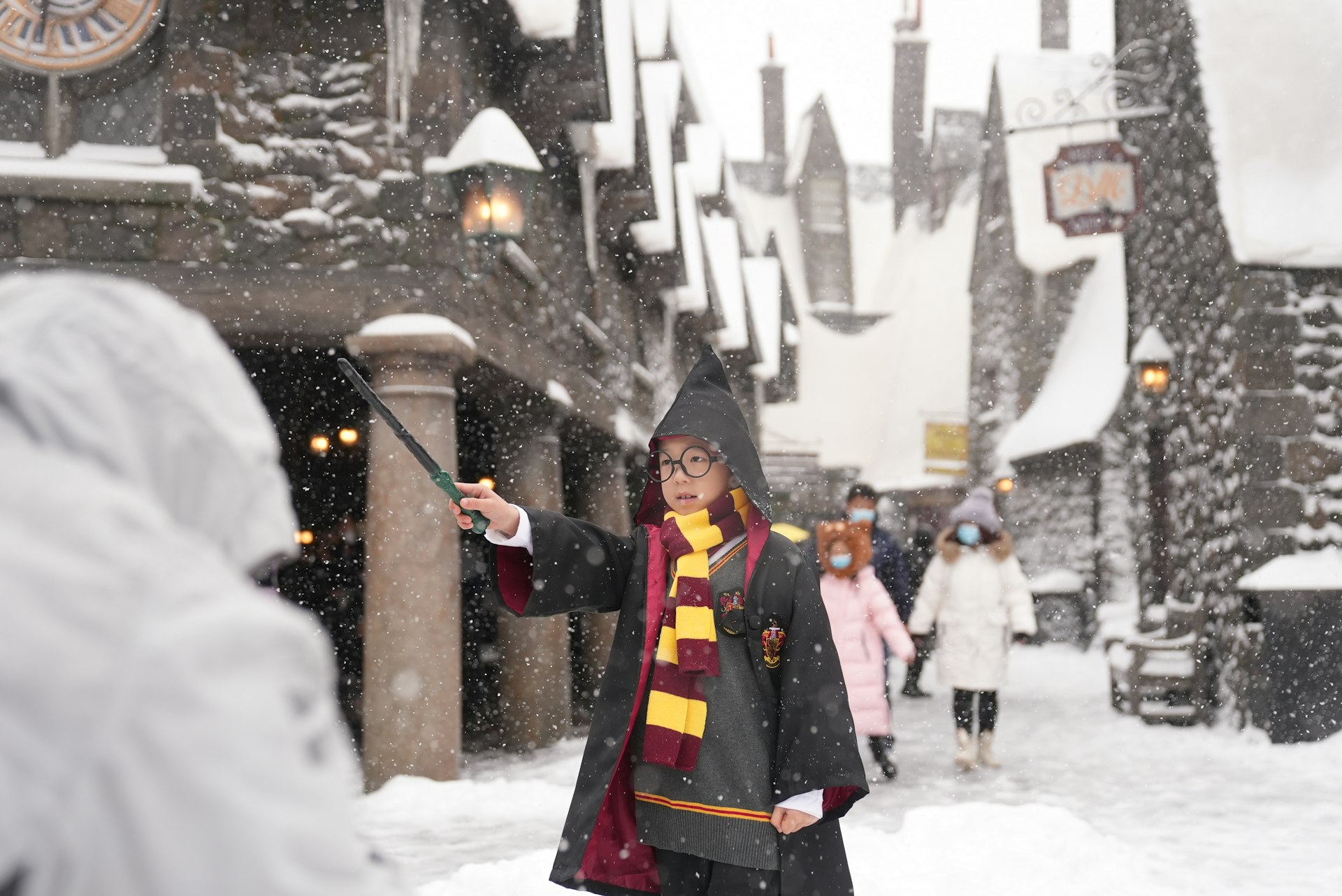 A child dressed as Harry Potter holds a wand in the snow at Universal Studios, Beijing, China