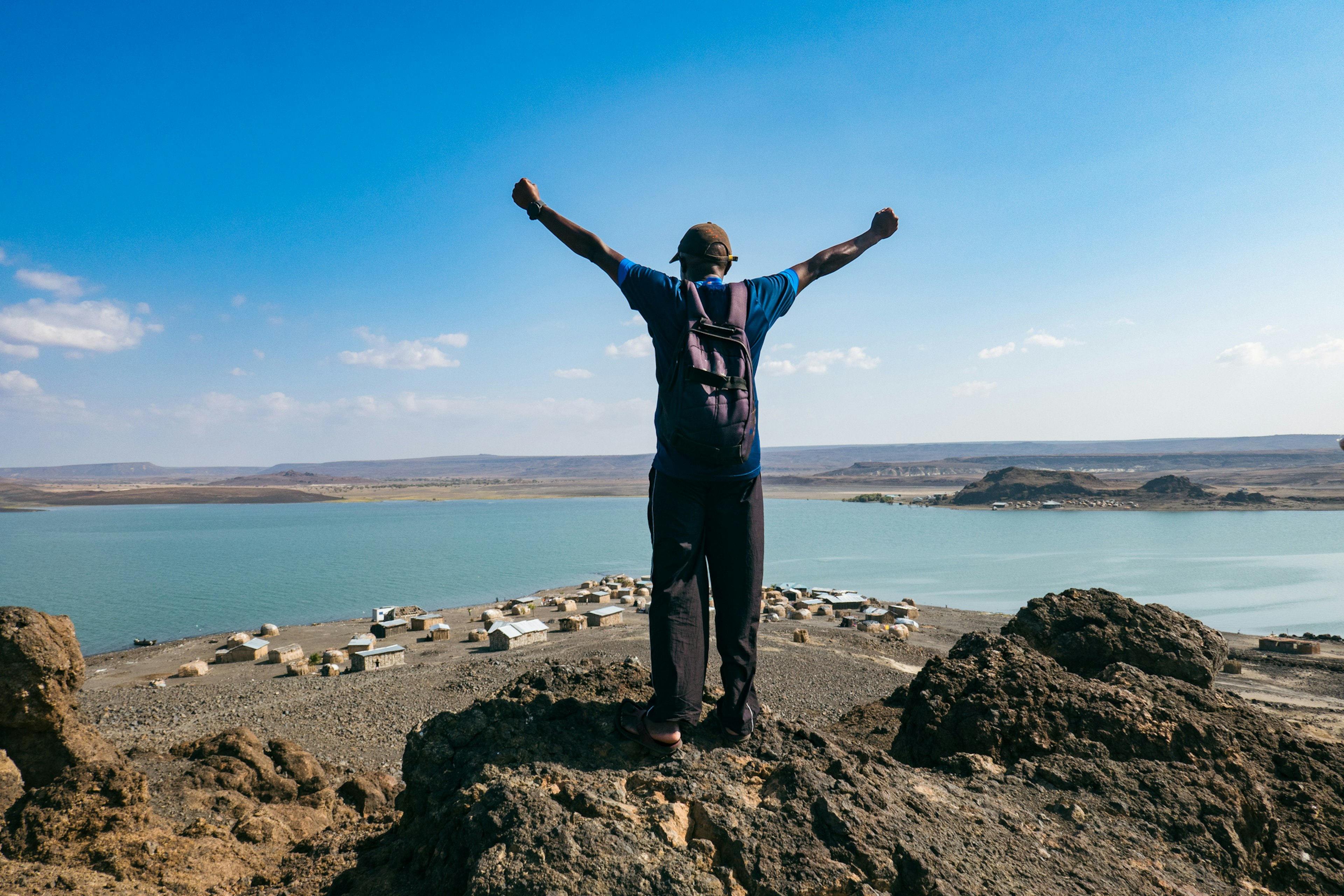 Rear View Of A Man Standing On A Rock Against The Background Of El Molo Villagei, Kenya in Lake Turkana National Parks