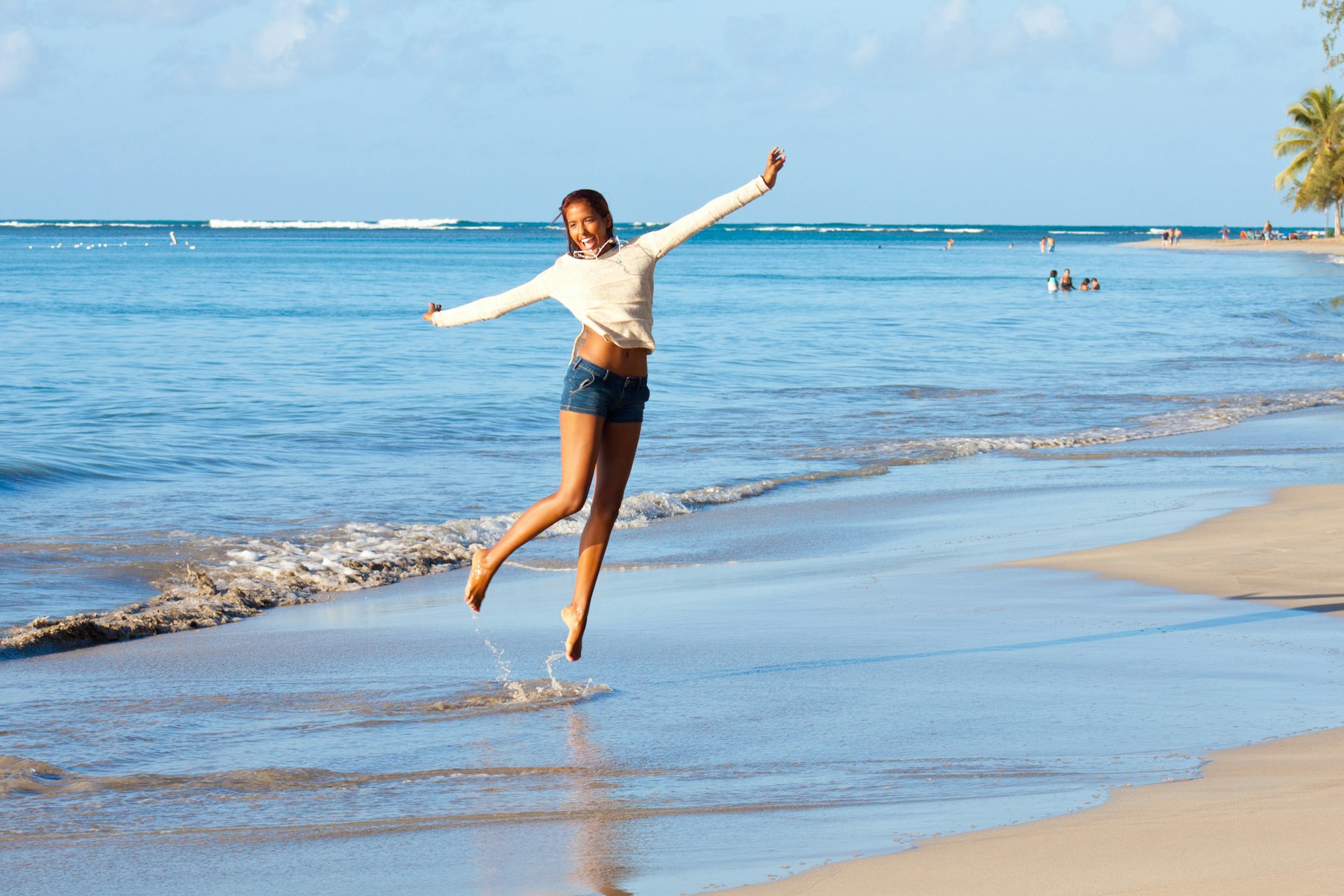 Woman jumping in the air at the shoreline of a beach in Puerto Rico
