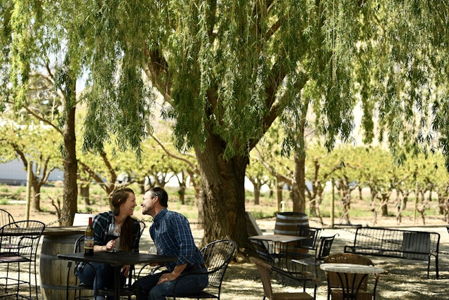 A couple sits in the shade enjoying wine at La Belle Vie winery, Palisade, Colorado, USA