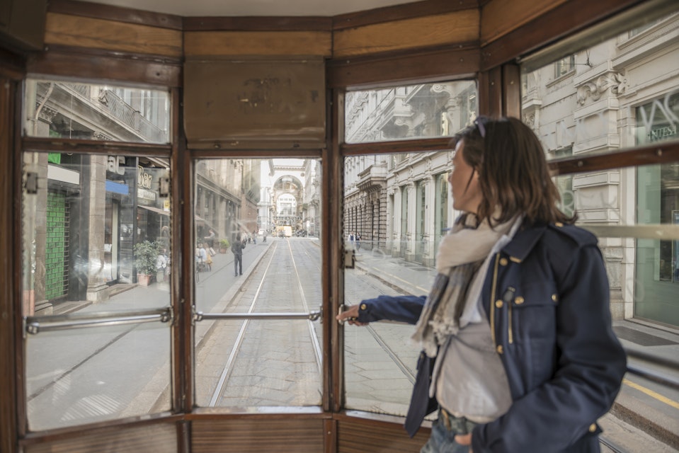 Woman traveling in a tram and looking out through window in Milan, Italy.