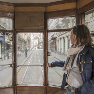 Woman traveling in a tram and looking out through window in Milan, Italy.