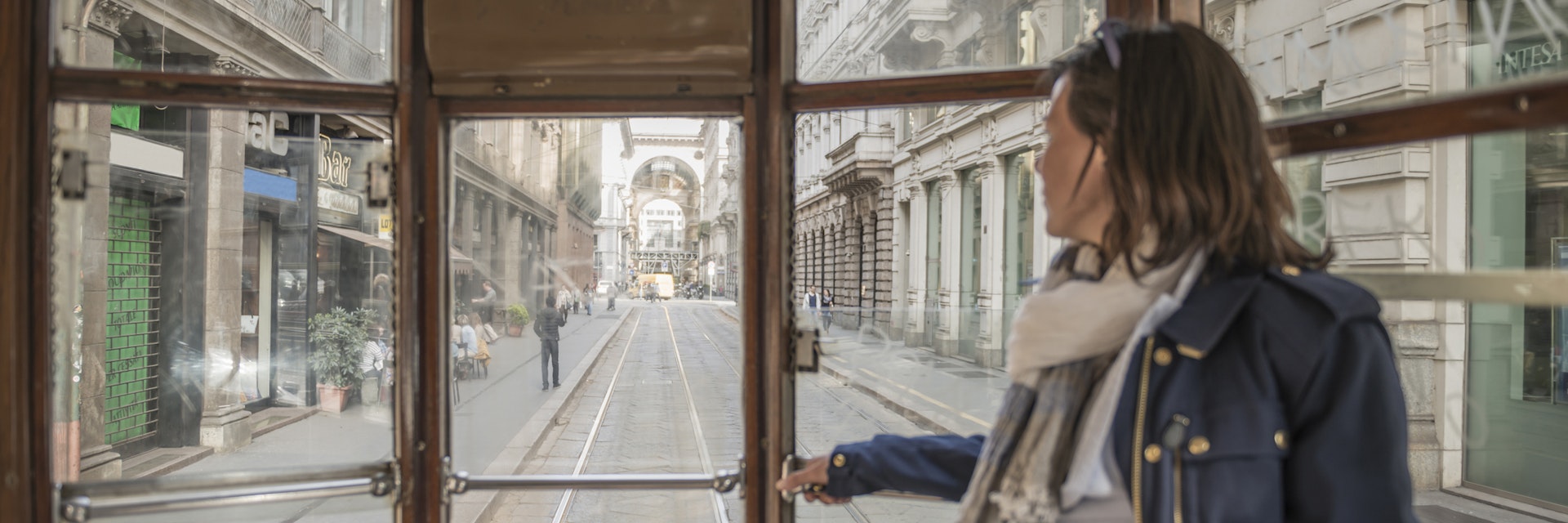 Woman traveling in a tram and looking out through window in Milan, Italy.