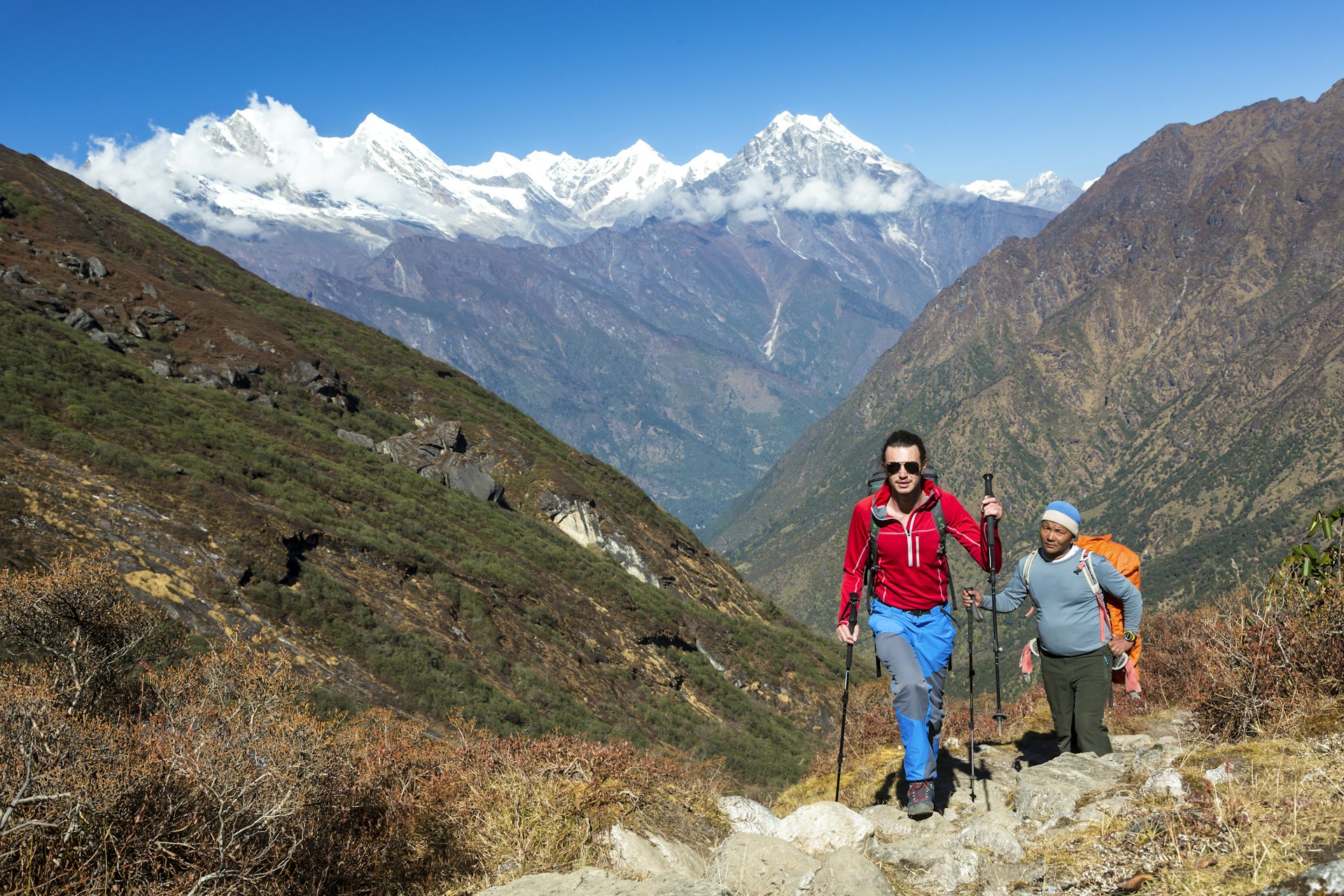 A hiker walking on a mountain trail along with local guide, Nepal, Asia