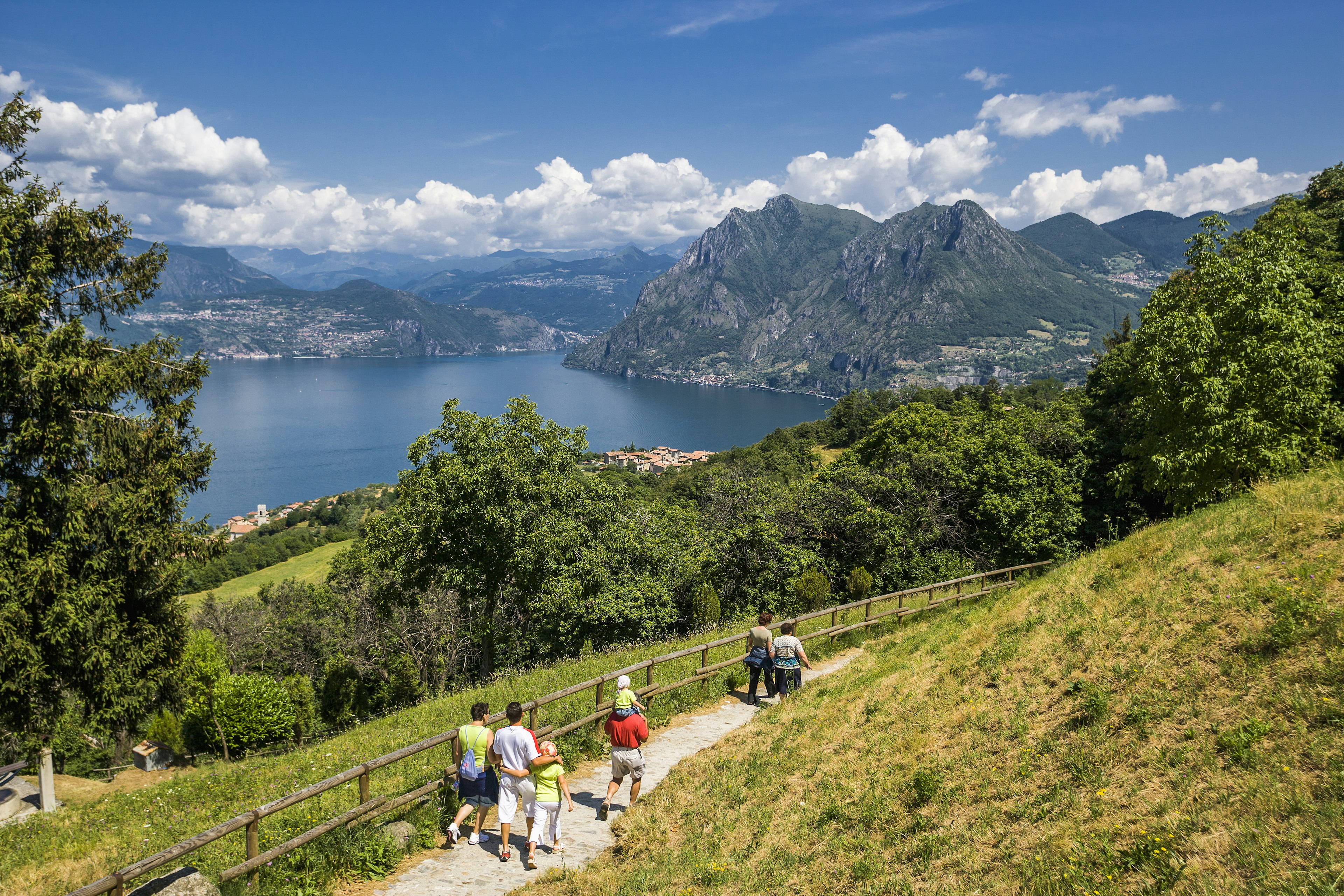 People walk on a path beside a beautiful lake in Italy.