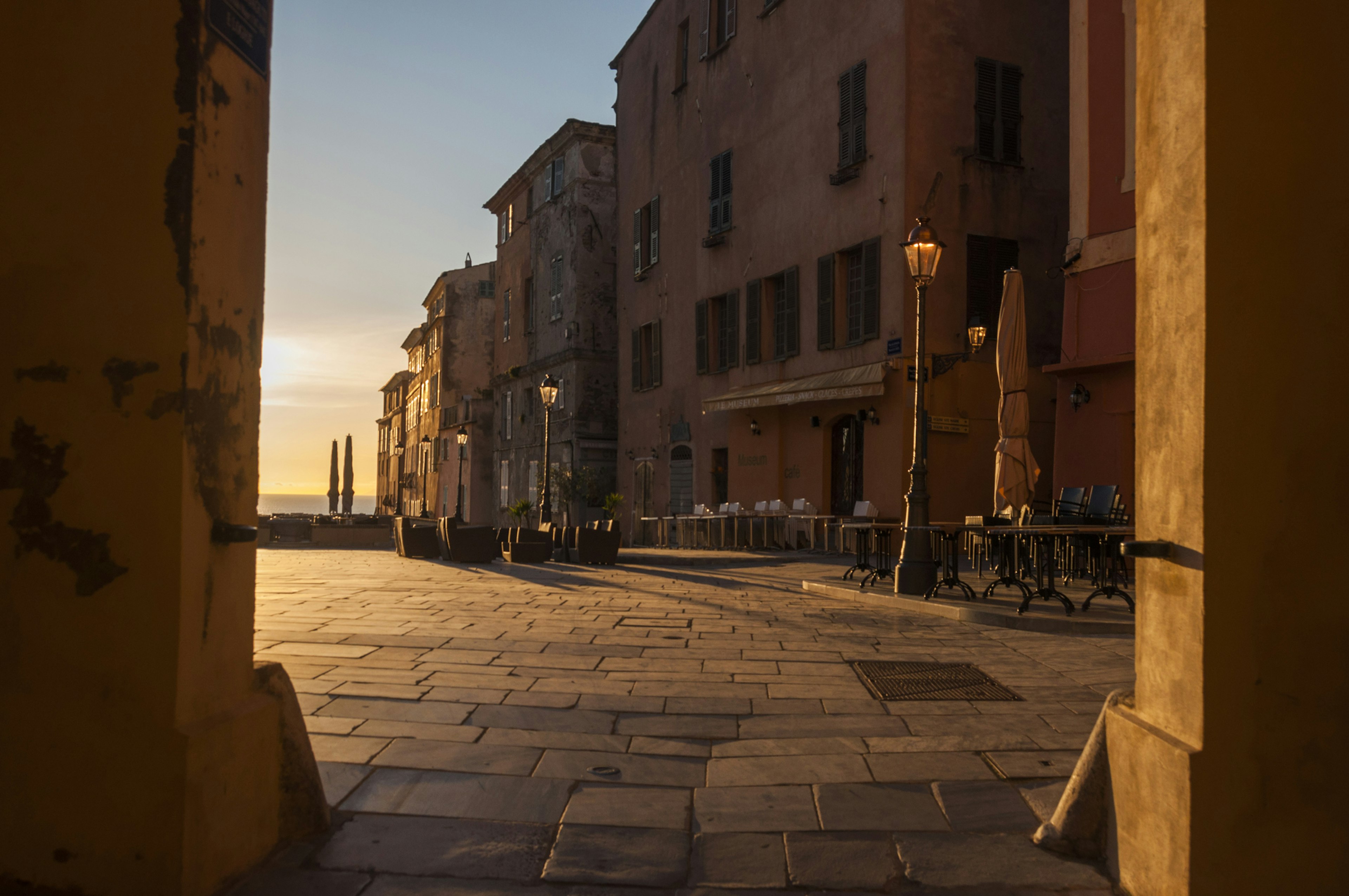 A paved street surrounded by old buildings in Bastia's old town bathed in late afternoon sunshine