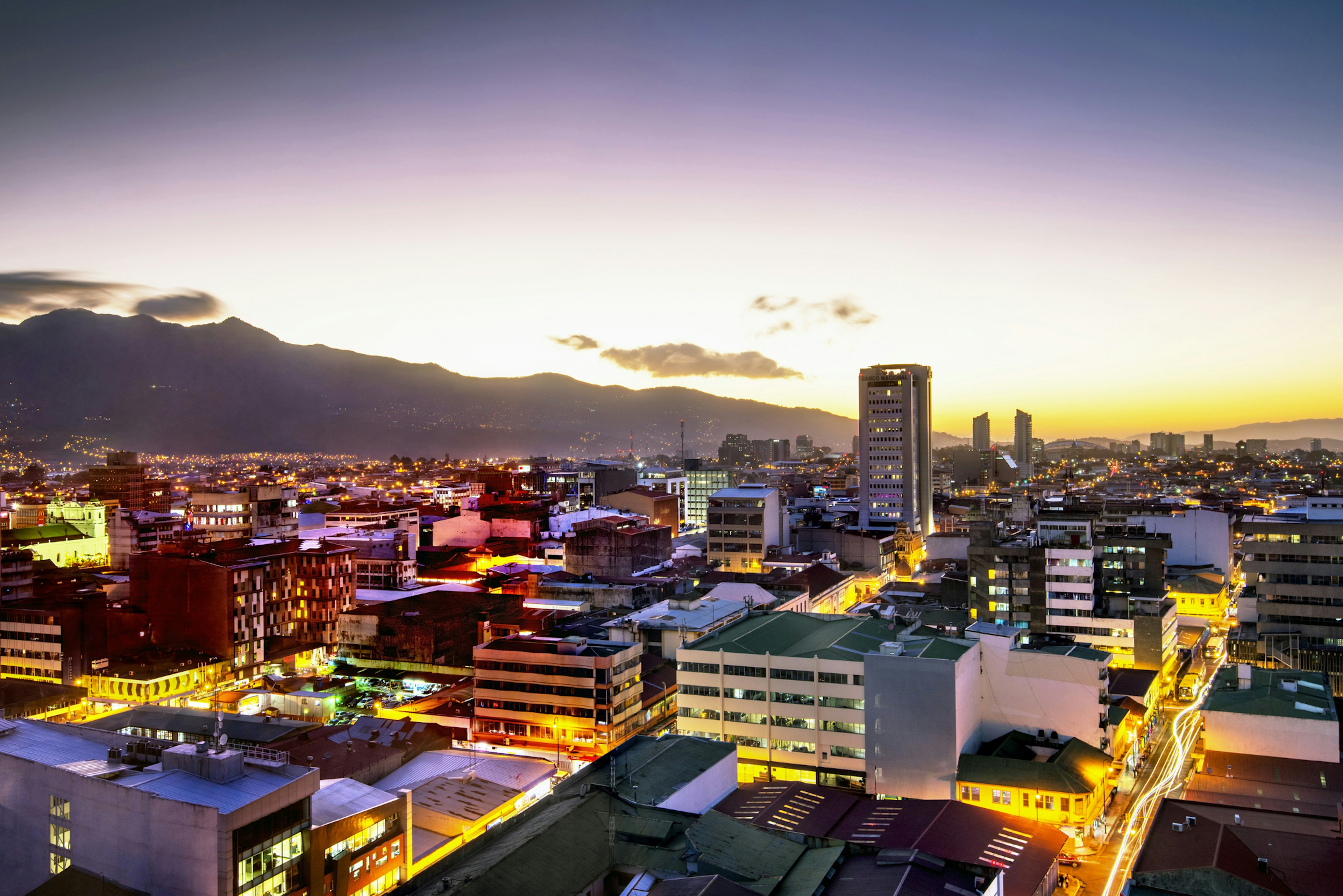 A cityscape at night backed by mountains