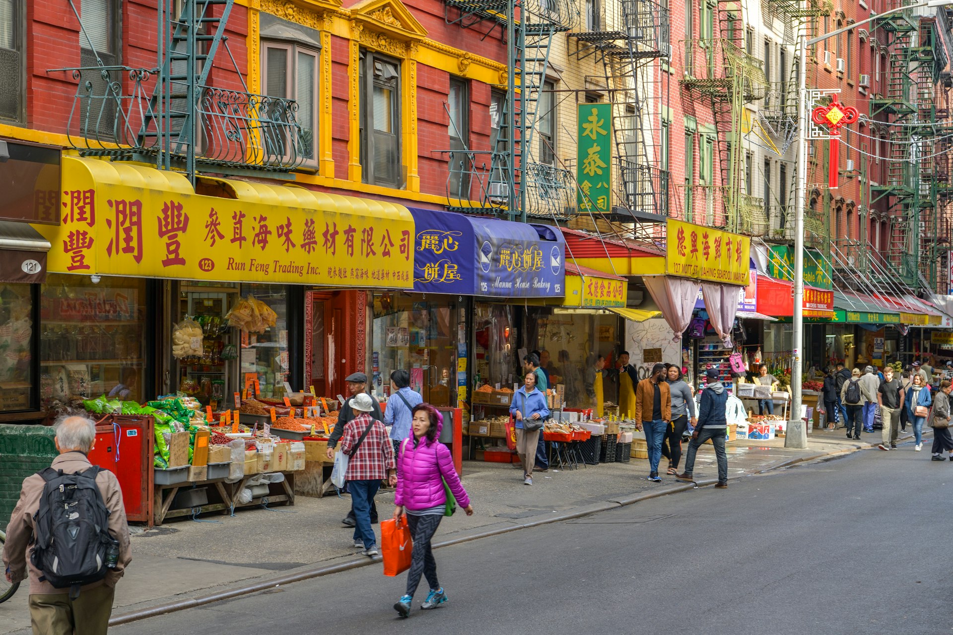 People walking past colorful storefronts in the Chinatown district of Manhattan